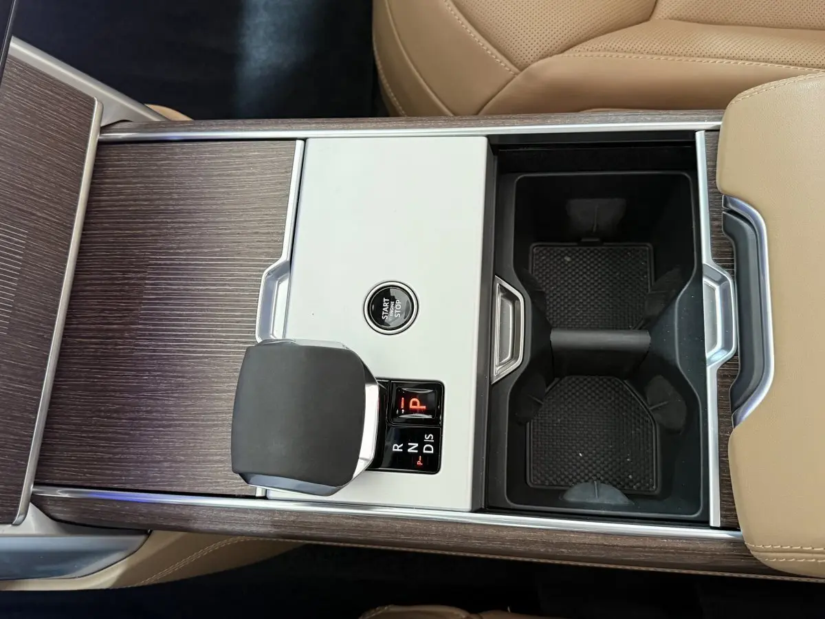 Vue plongeante sur la console centrale bois et aluminium avec levier de vitesse et bouton start/stop du Range Rover noir.