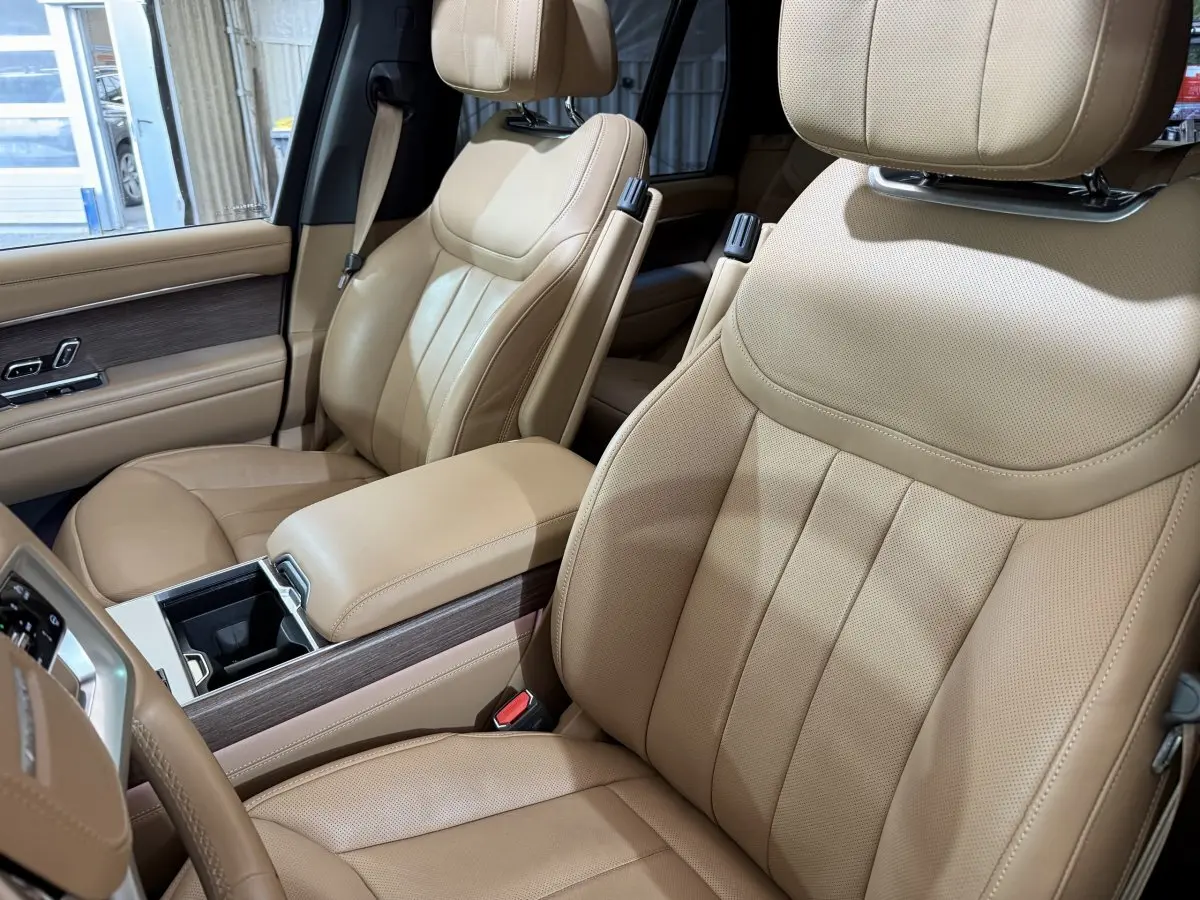 Vue intérieure rapprochée des sièges avant en cuir beige du Range Rover PHEV P550e Autobiography 2024.