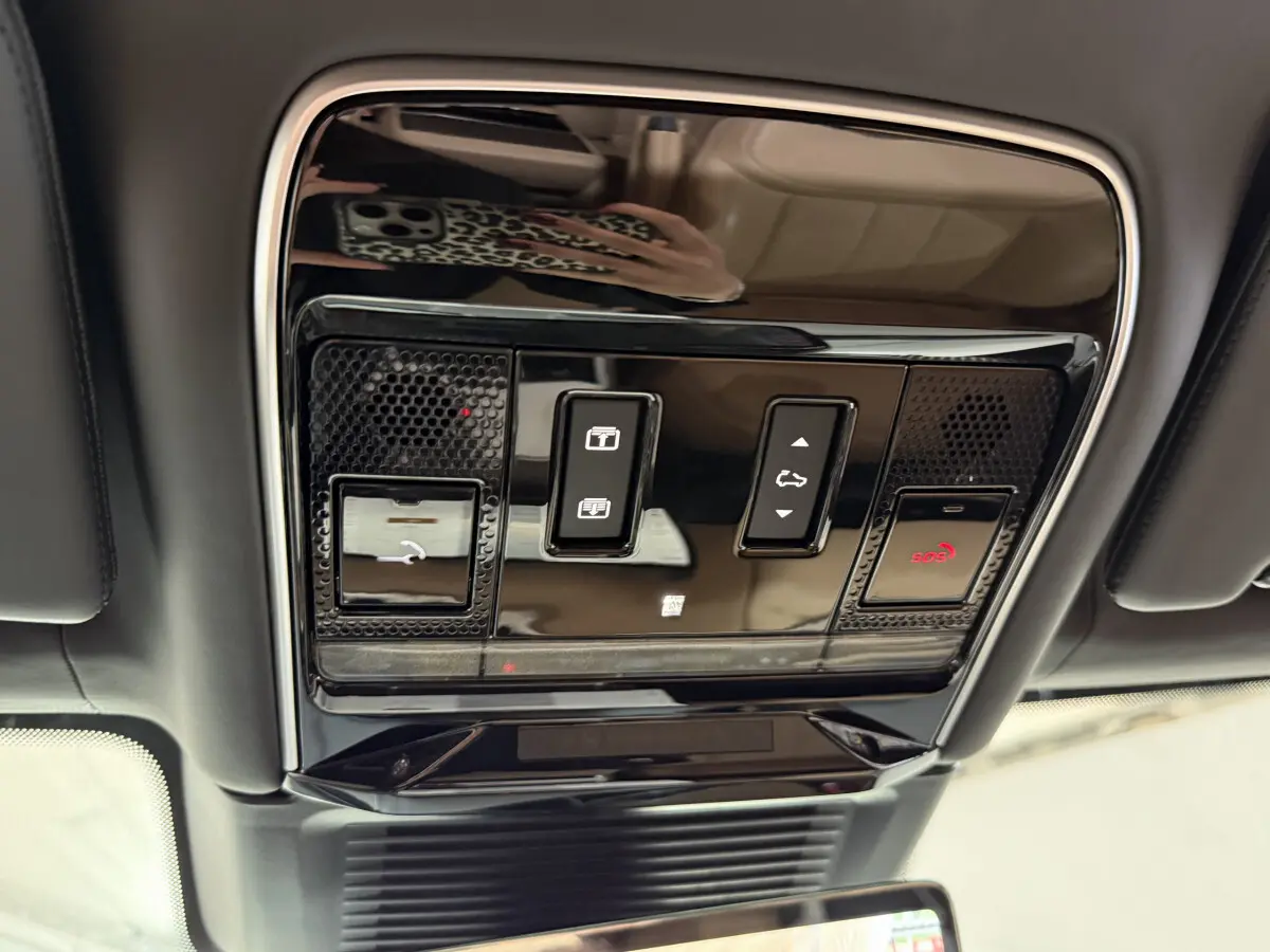 Vue intérieure du plafonnier noir brillant du Range Rover PHEV 2024 avec commandes de toit ouvrant et SOS.