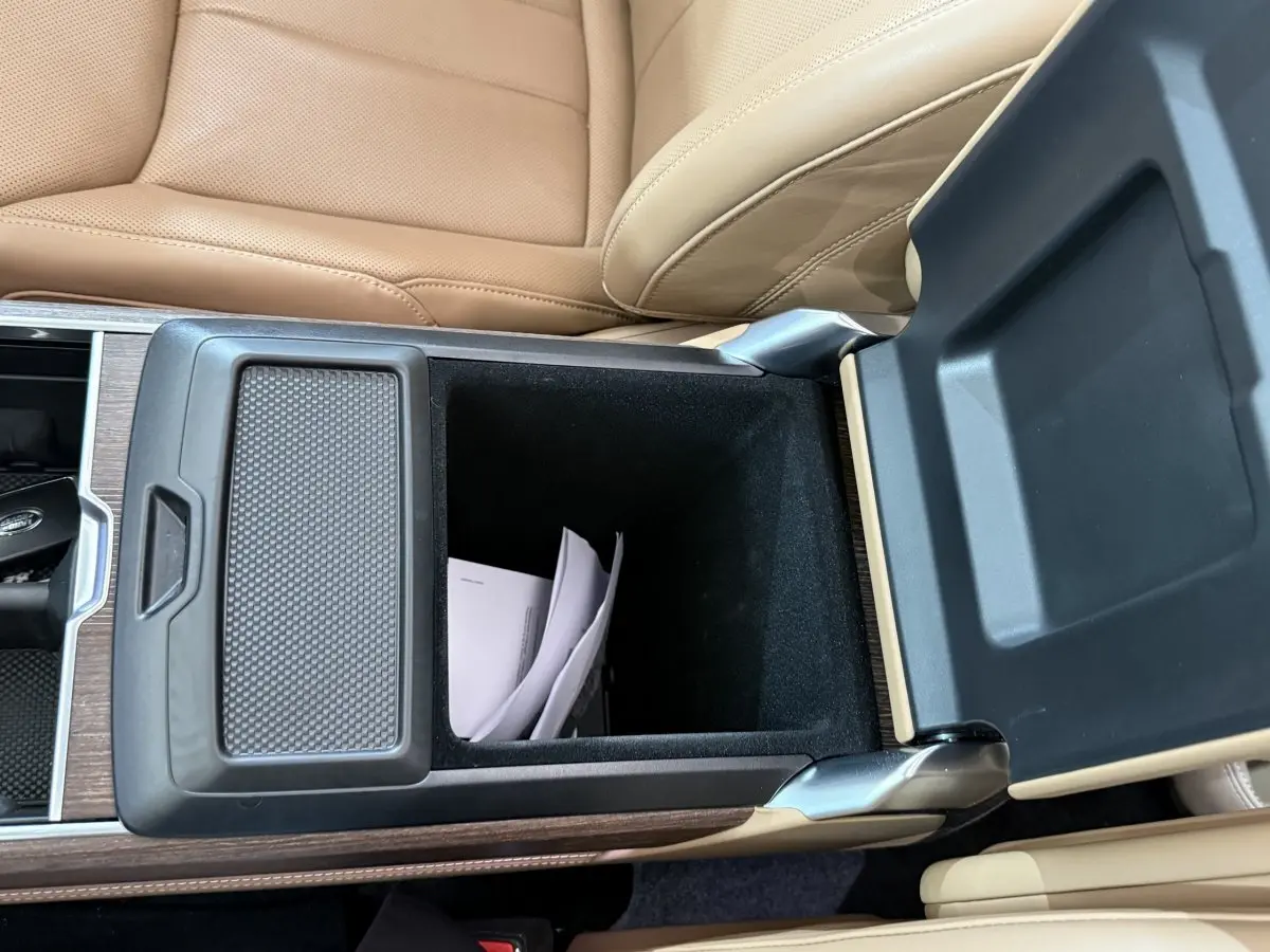 Vue rapprochée de la console centrale ouverte du Range Rover PHEV 2024, cuir beige et insert bois visible.