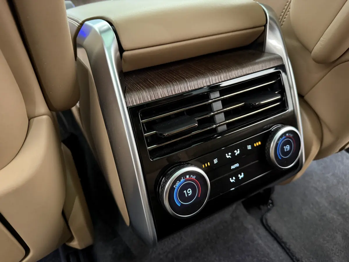 Détail de la console de climatisation arrière beige du Range Rover PHEV 2024 avec commandes digitales et aérateurs.