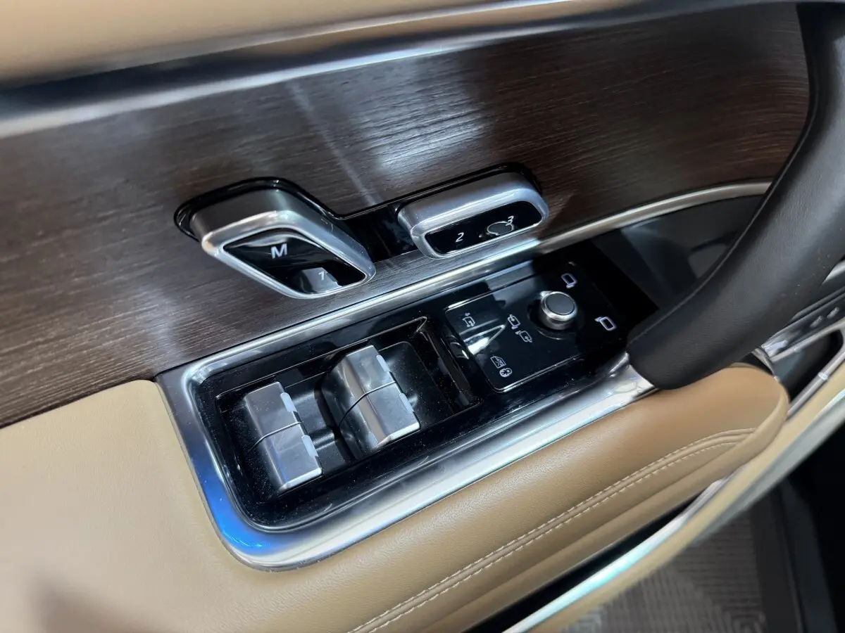 Détail des commandes de réglage des sièges et des vitres côté conducteur, garniture bois et cuir beige du Range Rover PHEV 2024.