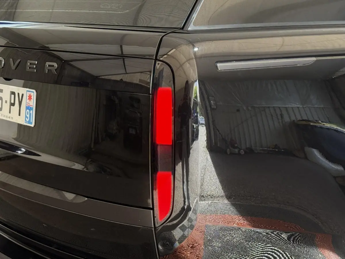 Gros plan sur le feu arrière droit noir brillant du Range Rover PHEV P550e 2024 avec plaque d’immatriculation française.