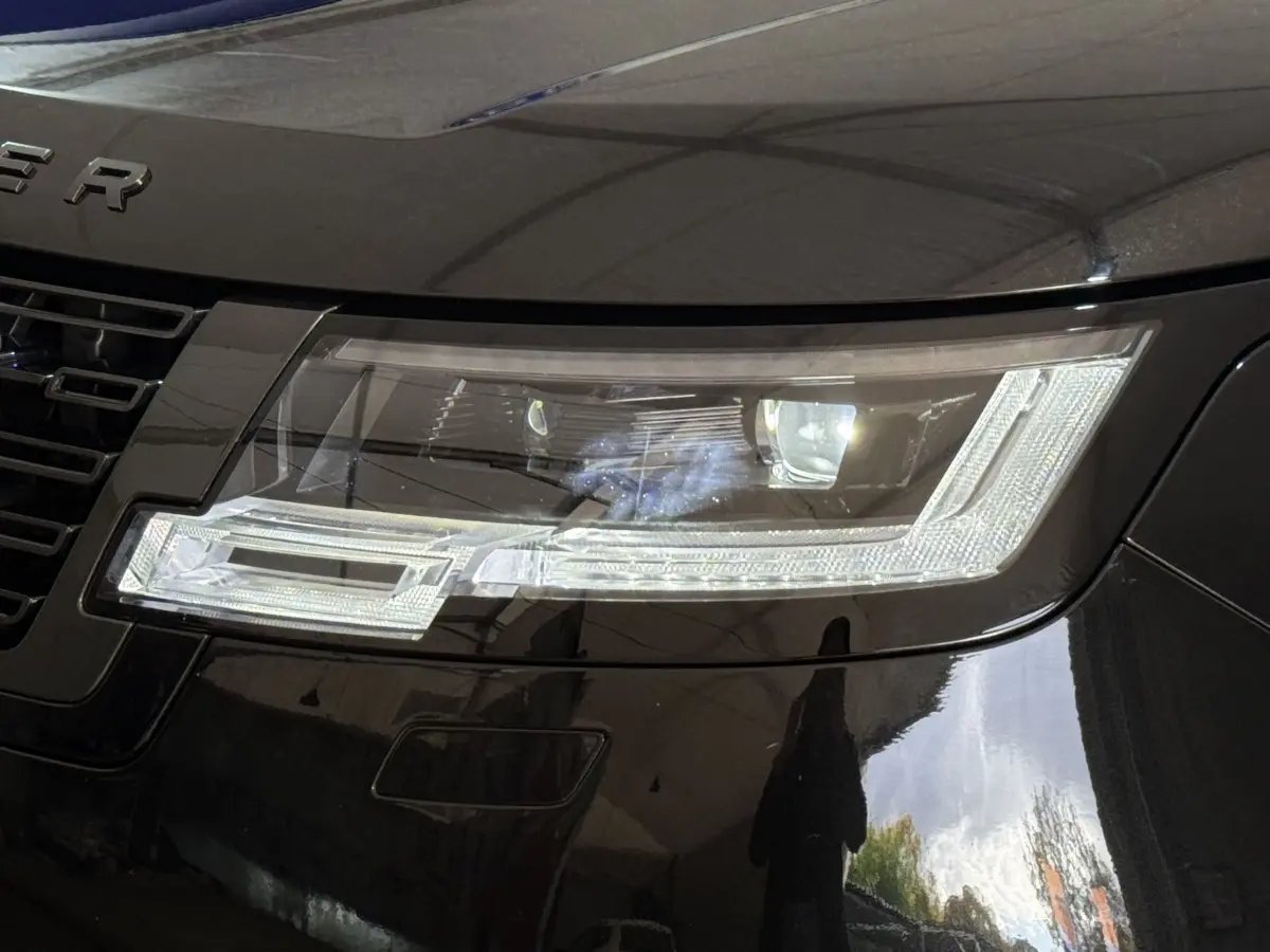 Gros plan sur le phare avant droit du Range Rover PHEV P550e noir, mettant en valeur son design LED moderne.