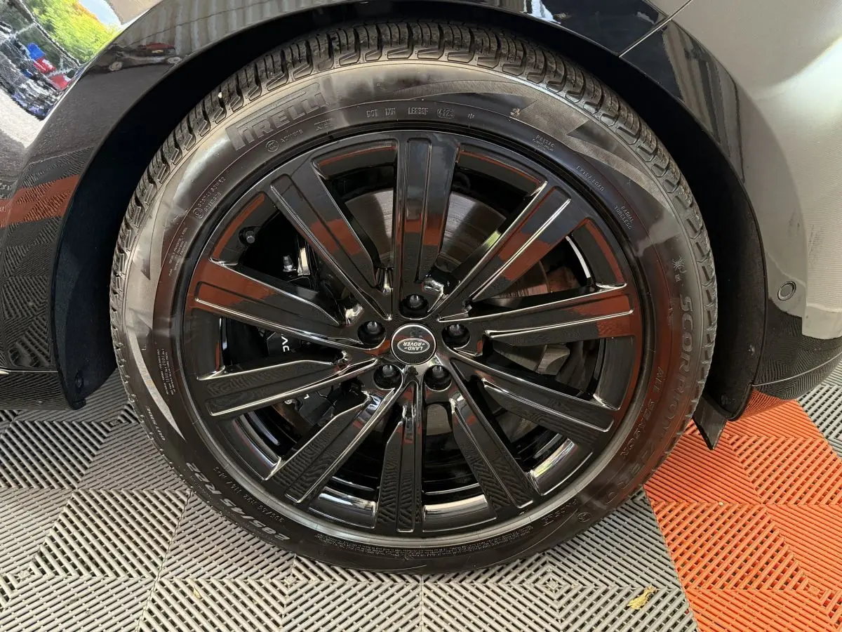 Gros plan sur la roue avant droite noire brillante du Range Rover PHEV P550e 2024 avec jante Land Rover.