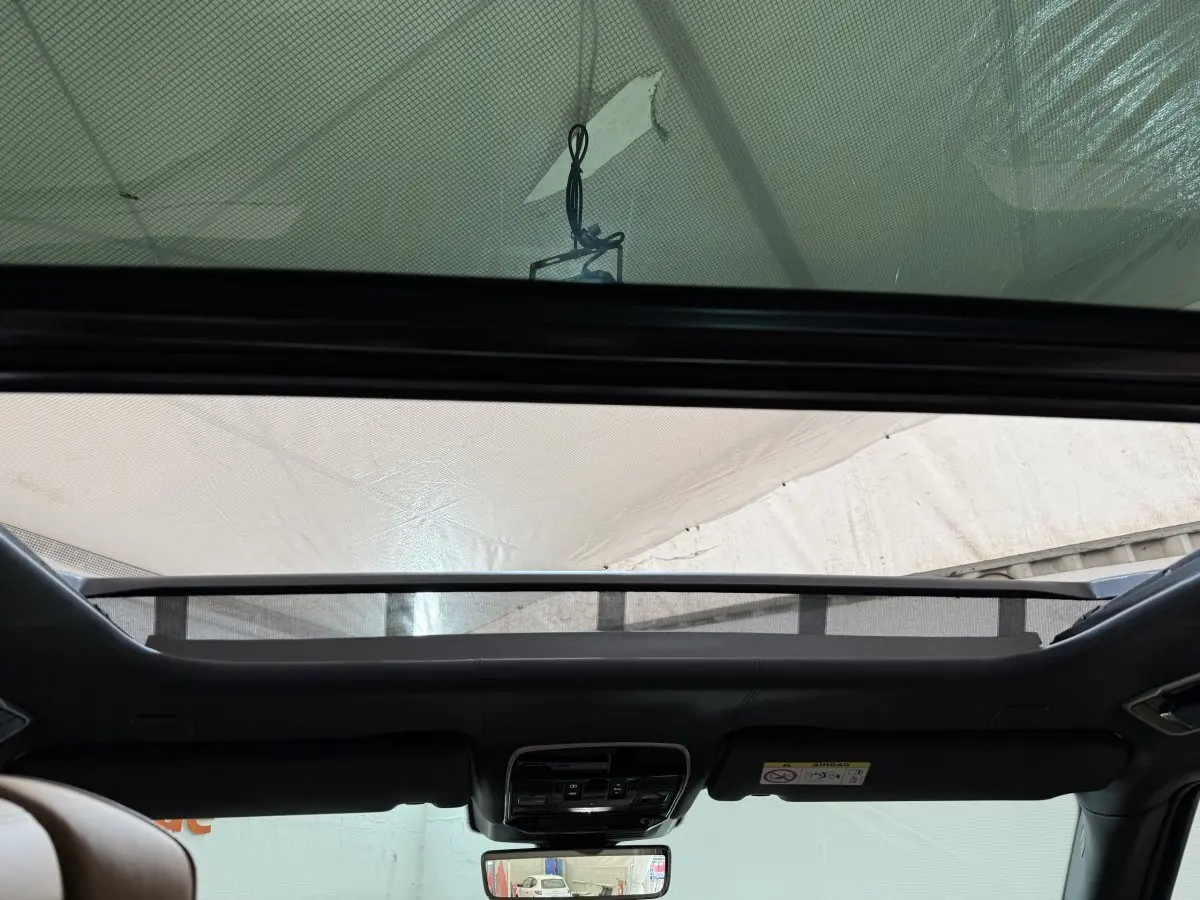 Vue intérieure vers le toit ouvrant en verre du Range Rover PHEV P550e noir, avec commandes et rétroviseur central visibles.