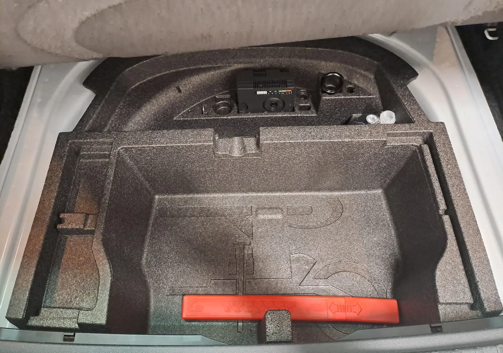 Coffre de rangement sous plancher dans un Skoda Octavia Combi blanc Moon, vu de dessus, avec compartiments en mousse noire.