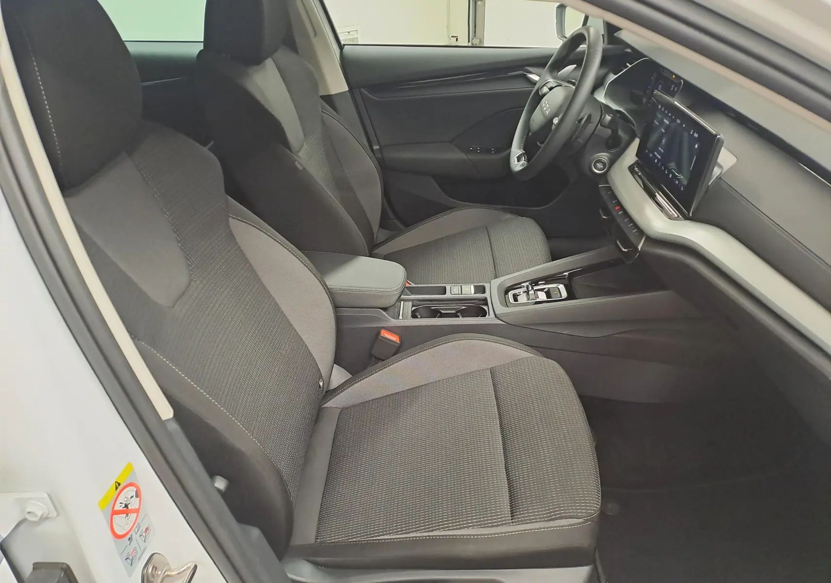 Vue intérieure côté conducteur de la Skoda Octavia Combi 2025, sièges tissu gris et tableau de bord moderne.