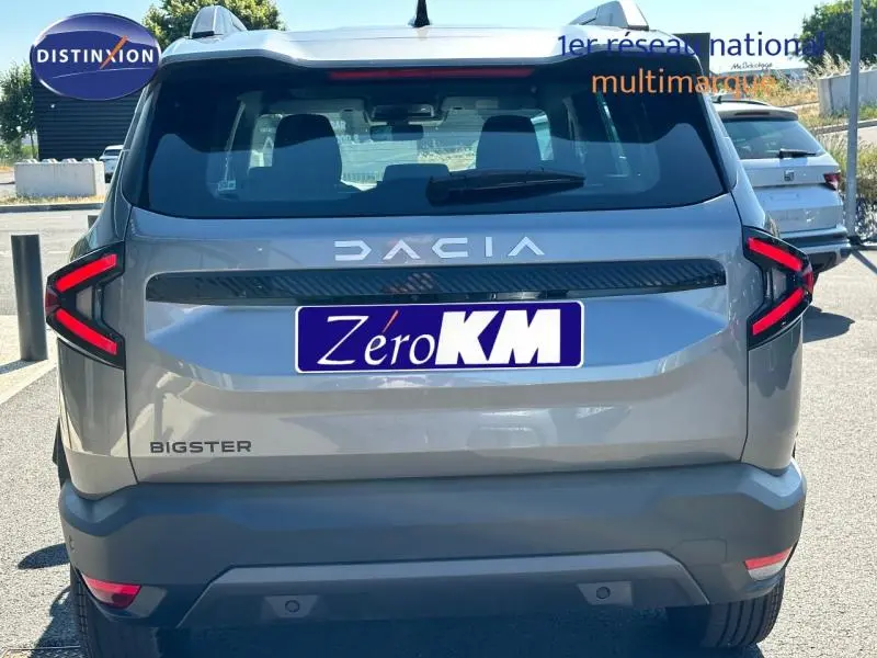 Vue arrière d'un Dacia Bigster blanc Glacier 2025 avec feux arrière LED en forme de C et logo DACIA lumineux.