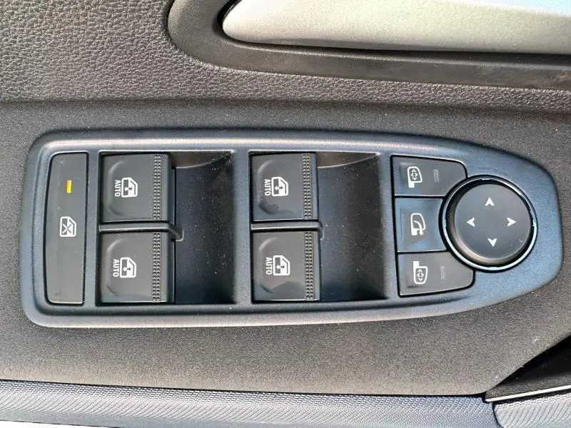 Gros plan sur les commandes de lève-vitres et réglage des rétroviseurs côté conducteur du Dacia Bigster blanc.