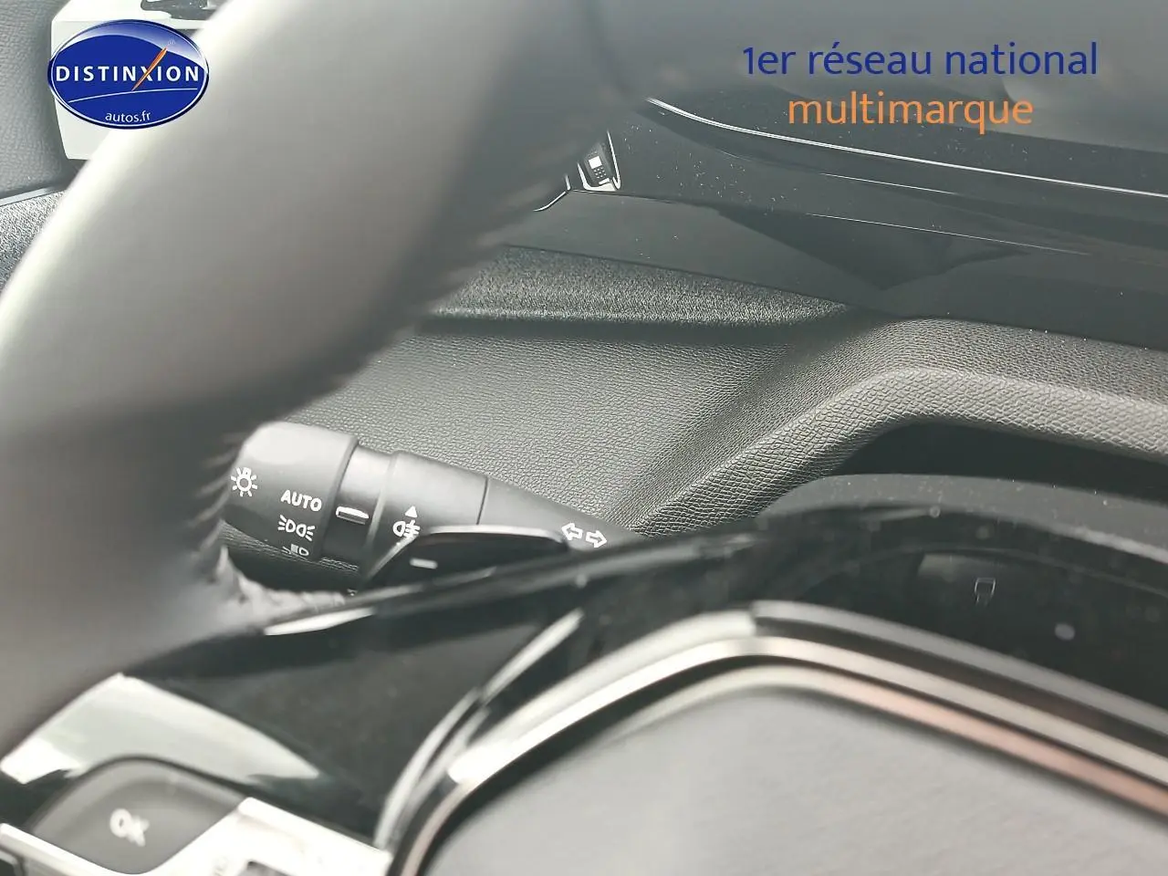 Détail intérieur du volant et du commodo d’éclairage de la Peugeot 308 SW gris sélénite, vue côté conducteur.