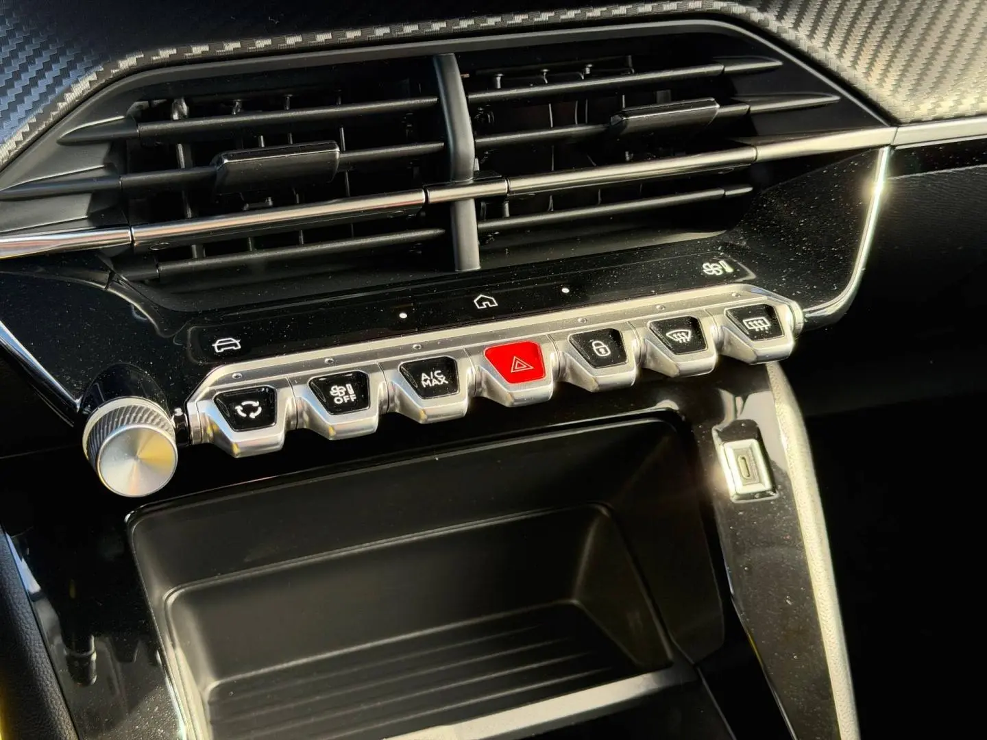 Vue rapprochée de la console centrale noire brillante avec boutons de commande et prise USB du Peugeot 208 gris Artense.