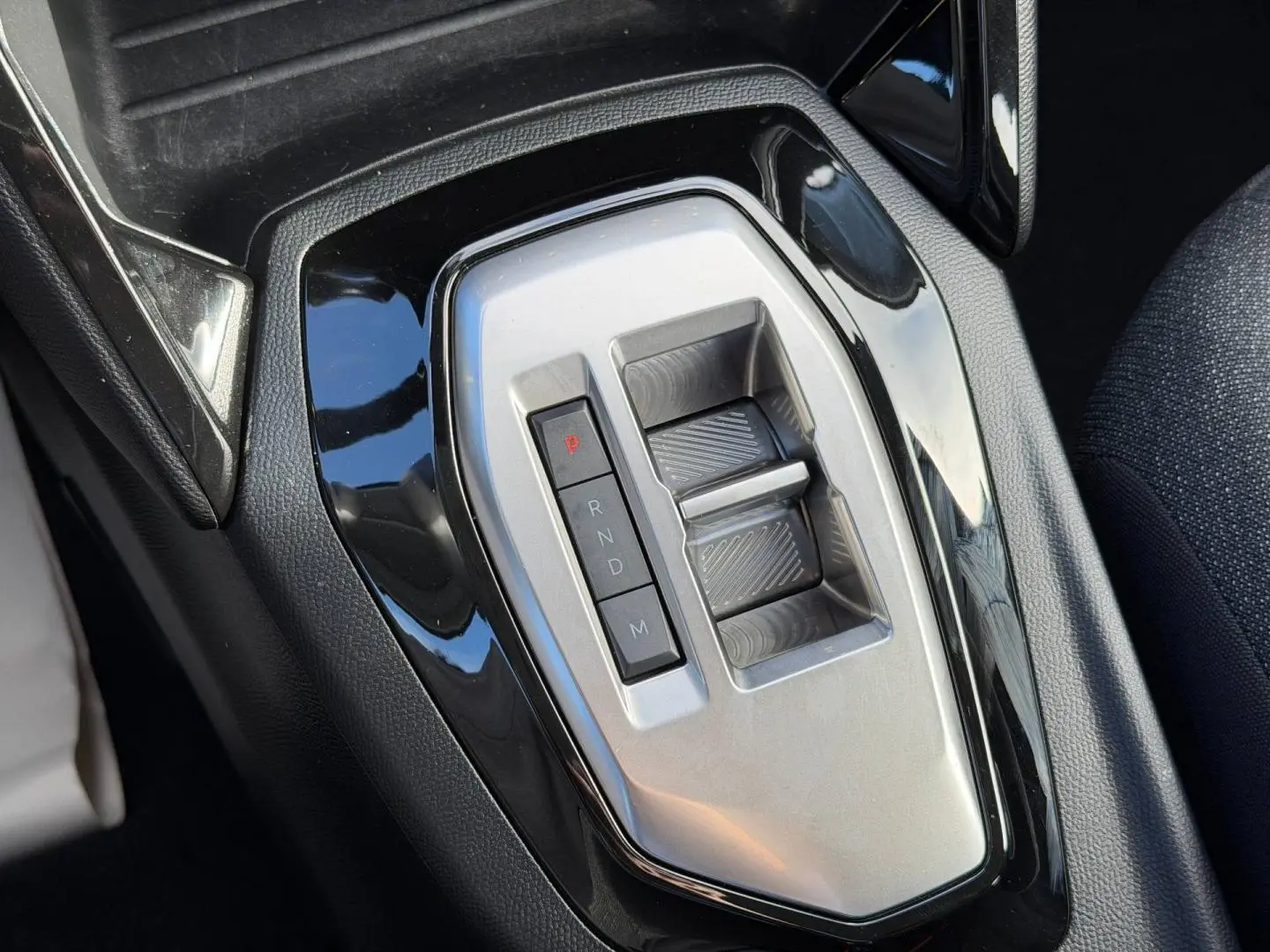 Gros plan sur la commande de boîte automatique argentée entourée de noir brillant dans l’habitacle du Peugeot 208 gris Artense.