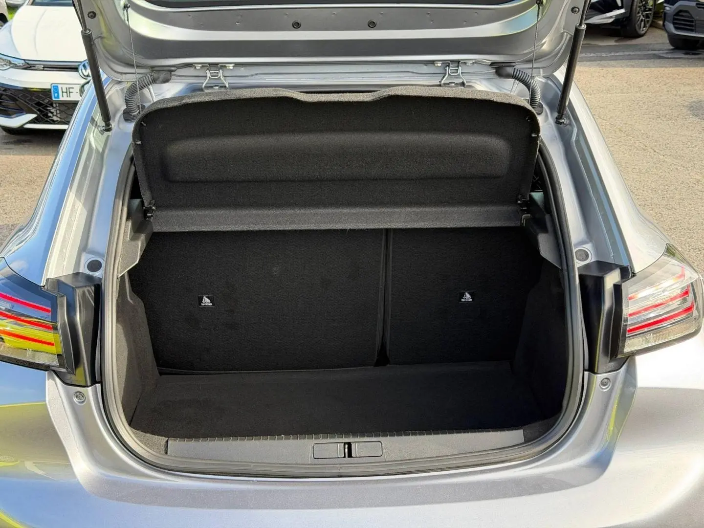 Coffre ouvert vu de l'arrière d'une Peugeot 208 gris Artense 2025, montrant l'espace de rangement vide.