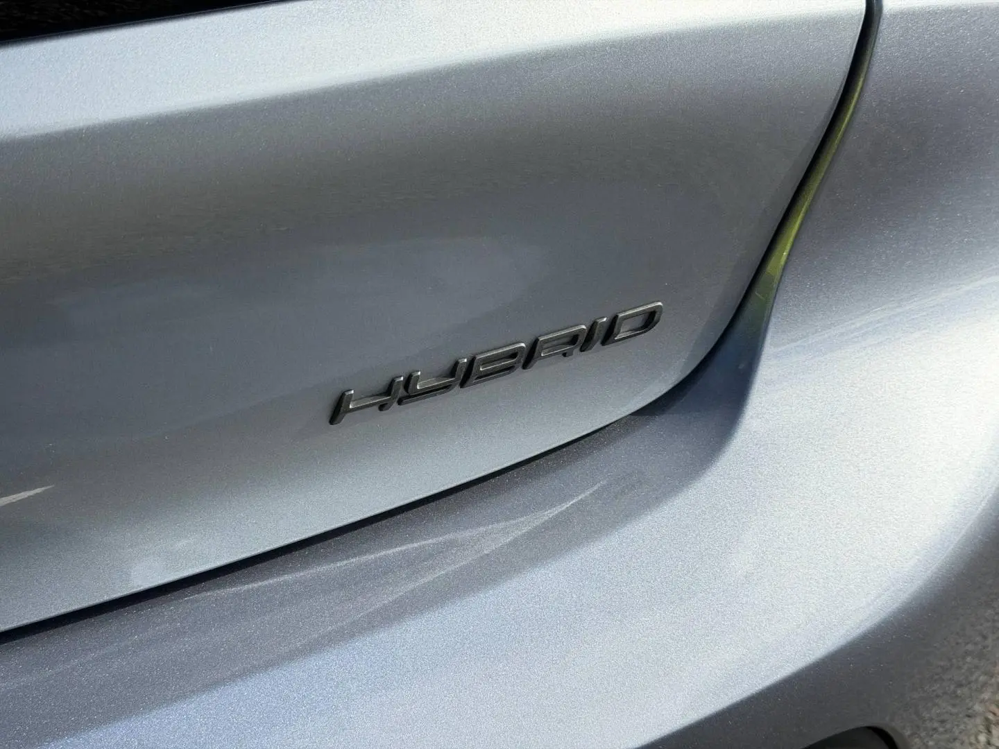 Gros plan sur l’arrière droit gris Artense d’une Peugeot 208 1.2 Hybrid avec logo "HYBRID" noir.