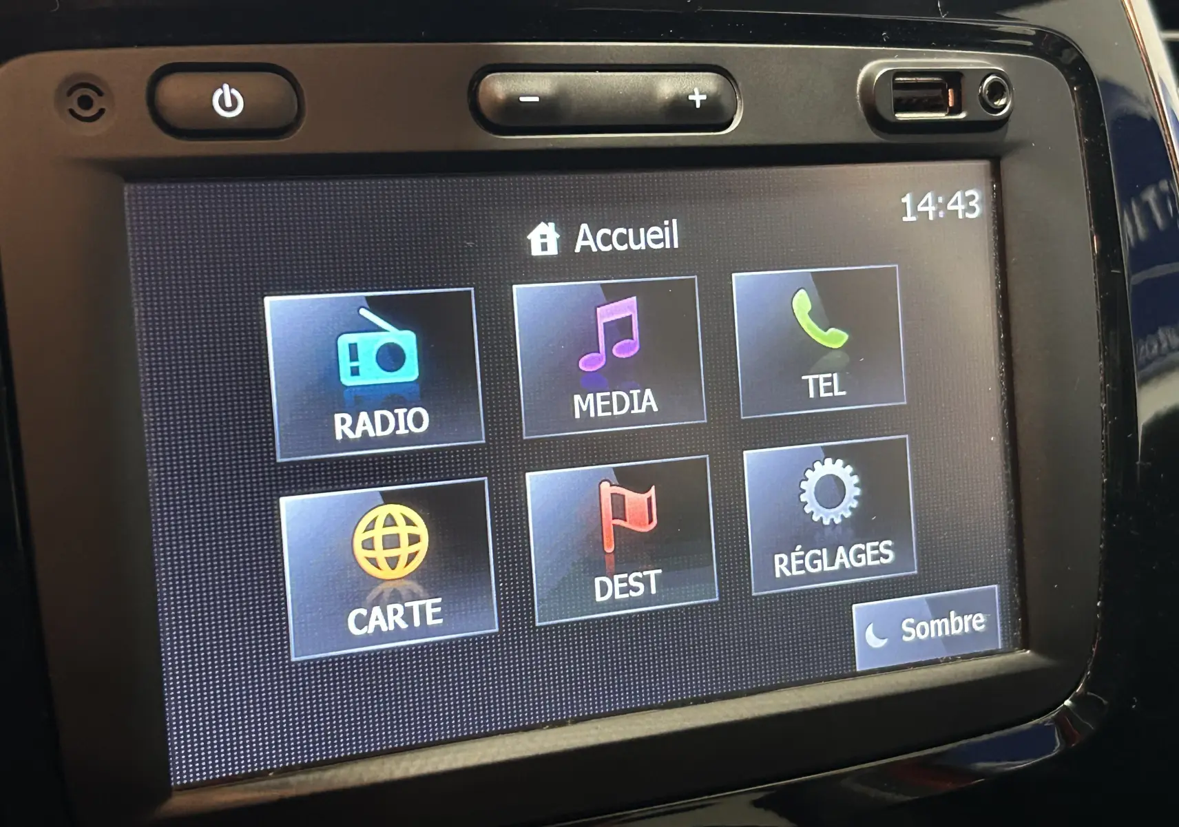 Écran tactile central du tableau de bord du Renault Captur orange, affichant le menu principal avec options radio, média et GPS.