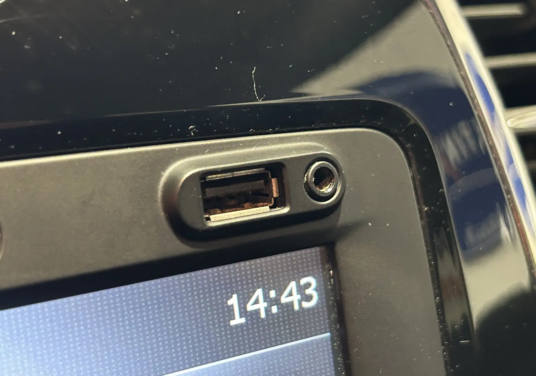 Gros plan sur la prise USB et la prise jack au-dessus de l'écran multimédia noir du Renault Captur orange 2014.