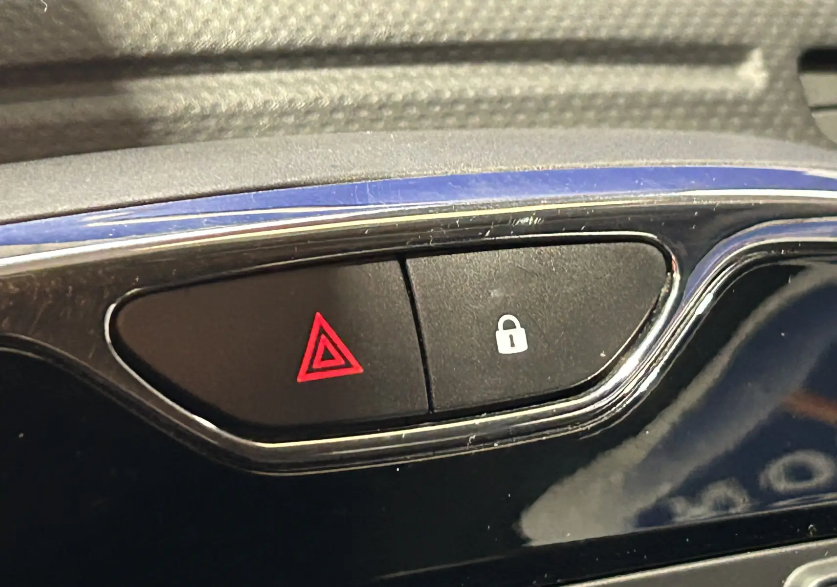 Gros plan sur les boutons de signal d'alerte et verrouillage centralisé sur la console noire brillante d'un Renault Captur orange.