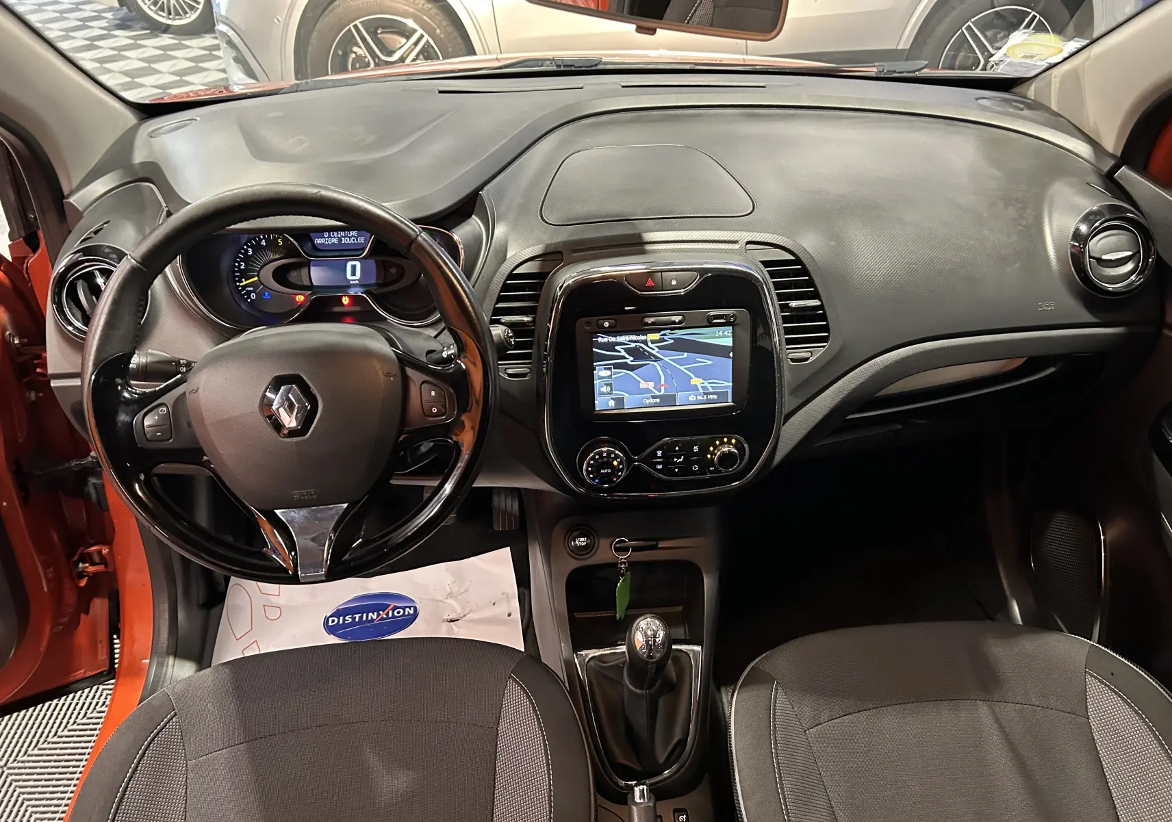 Vue intérieure du tableau de bord du Renault Captur orange 2014 avec GPS et boîte manuelle visible.