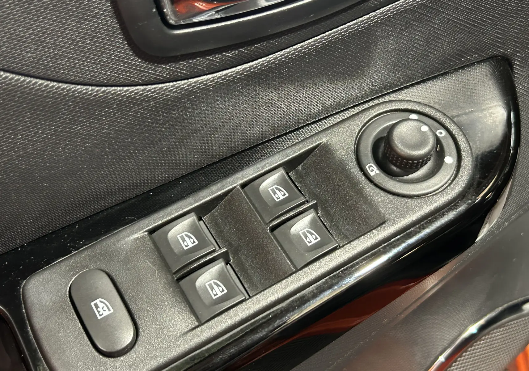 Commande des vitres électriques et réglage des rétroviseurs côté conducteur dans une Renault Captur orange 2014.