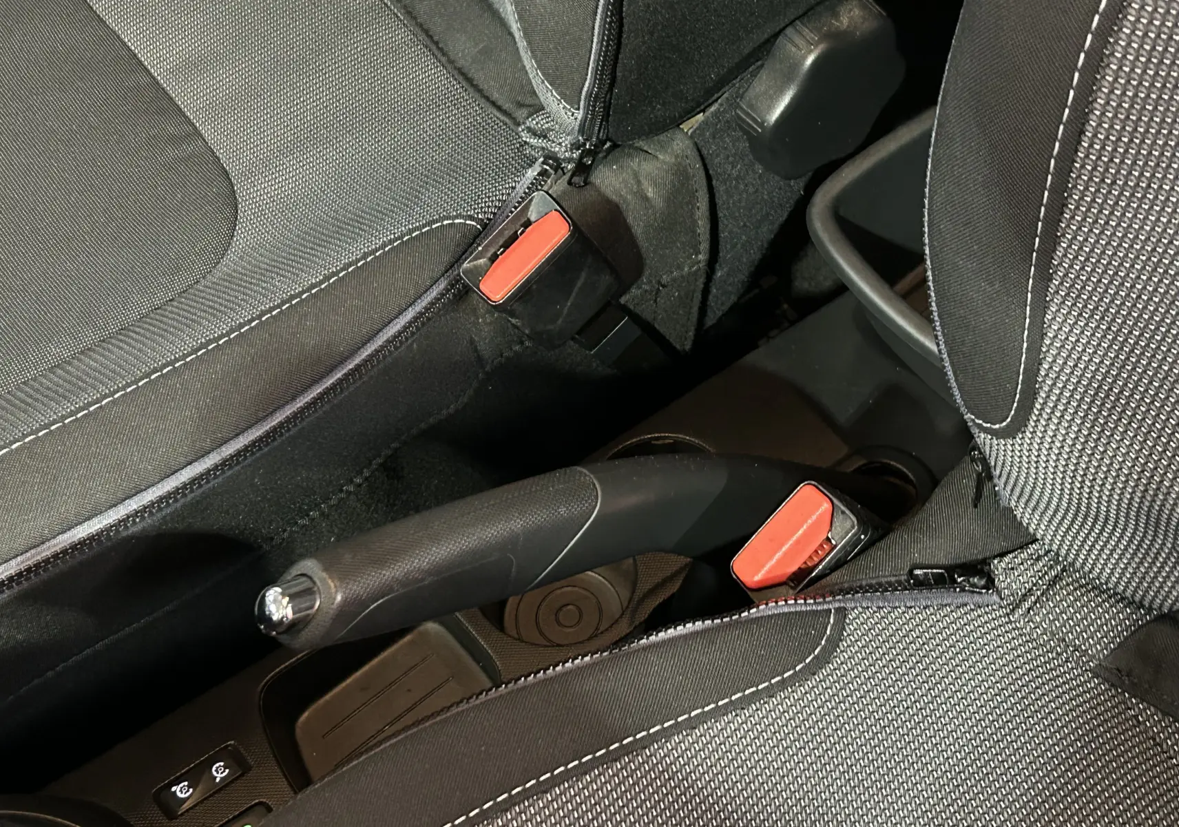 Gros plan intérieur sur le frein à main et les ceintures noires avec surpiqûres blanches du Renault Captur dCi 90ch Intens 2014.