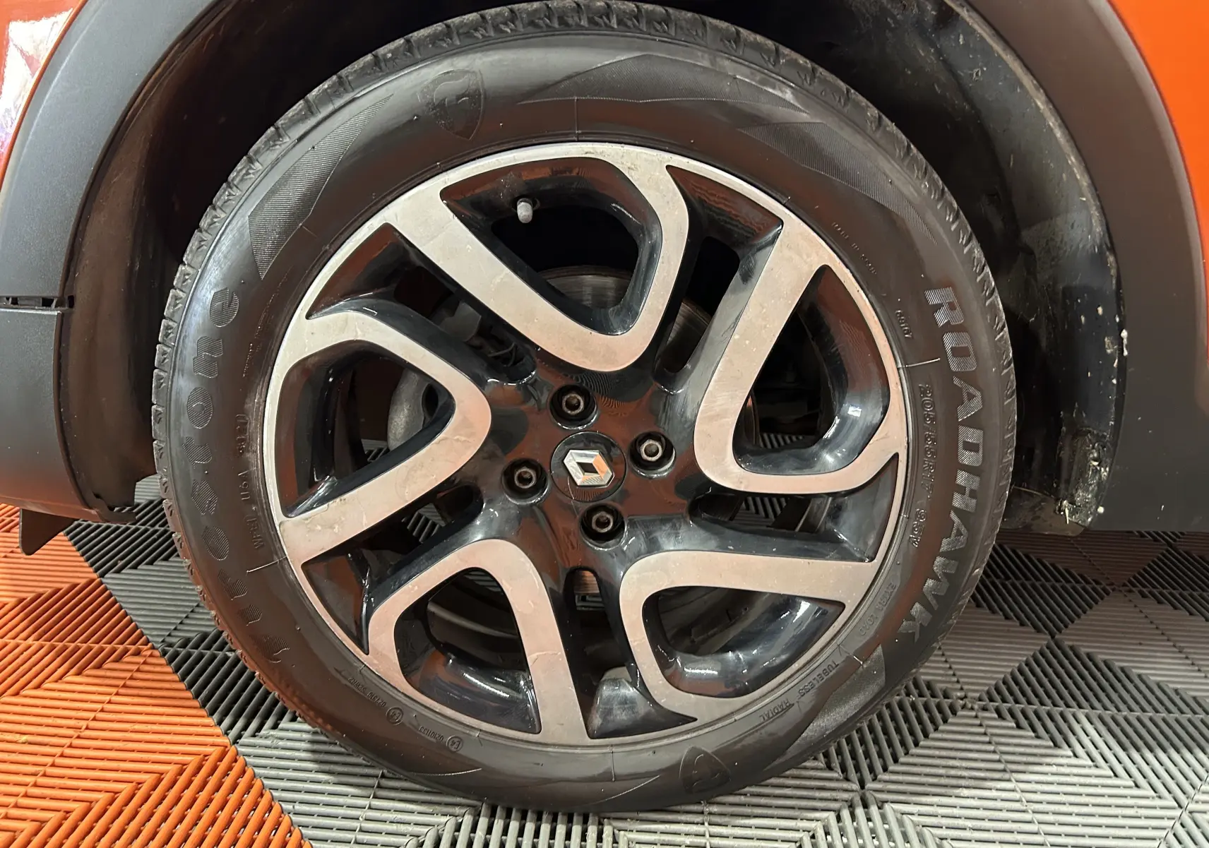 Gros plan sur la roue avant droite du Renault Captur orange de 2014 avec jante alliage au design moderne.