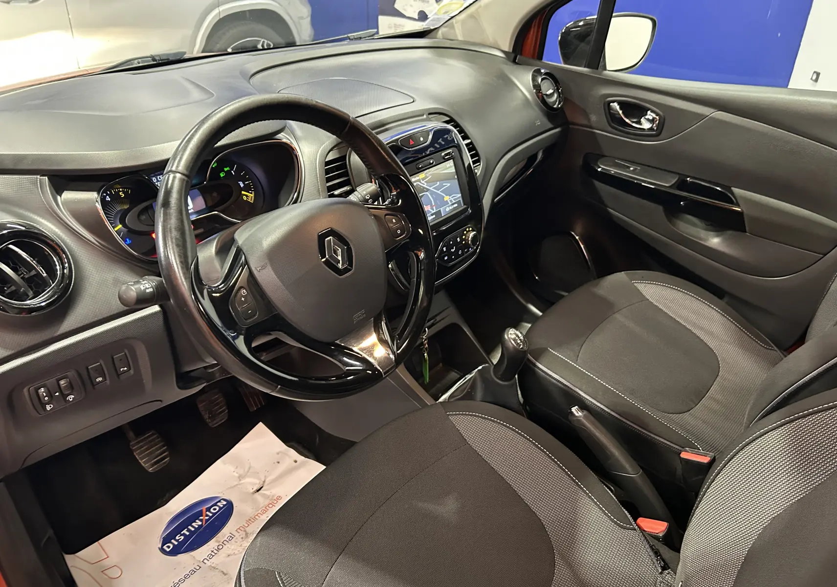 Intérieur avant droit du Renault Captur orange 2014, avec tableau de bord noir et écran GPS tactile visible.