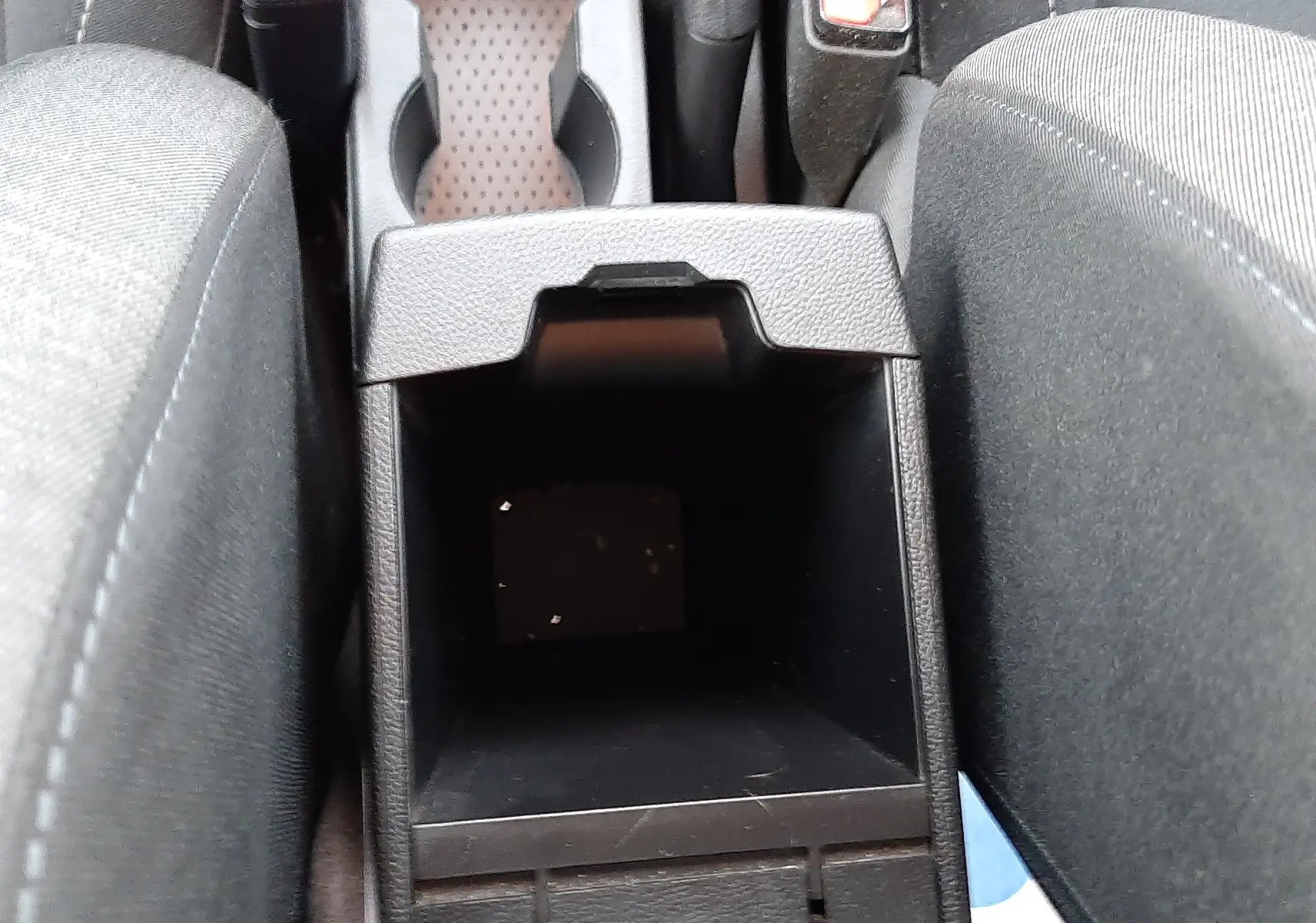 Vue plongeante sur le rangement central ouvert entre les sièges avant en tissu noir du Renault Captur 2020.