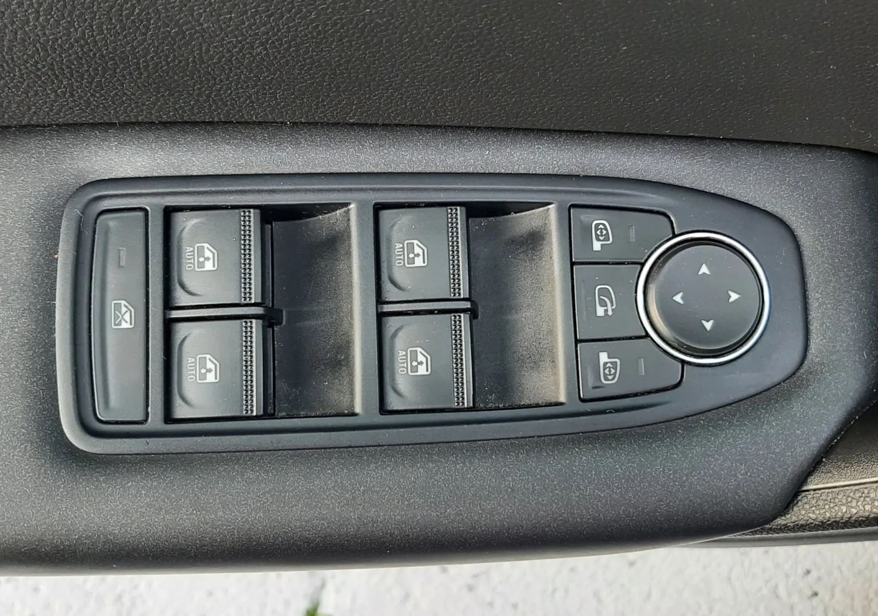 Panneau de commandes des vitres et rétroviseurs noirs sur la porte intérieure d'un Renault Captur bleu iron toit noir.