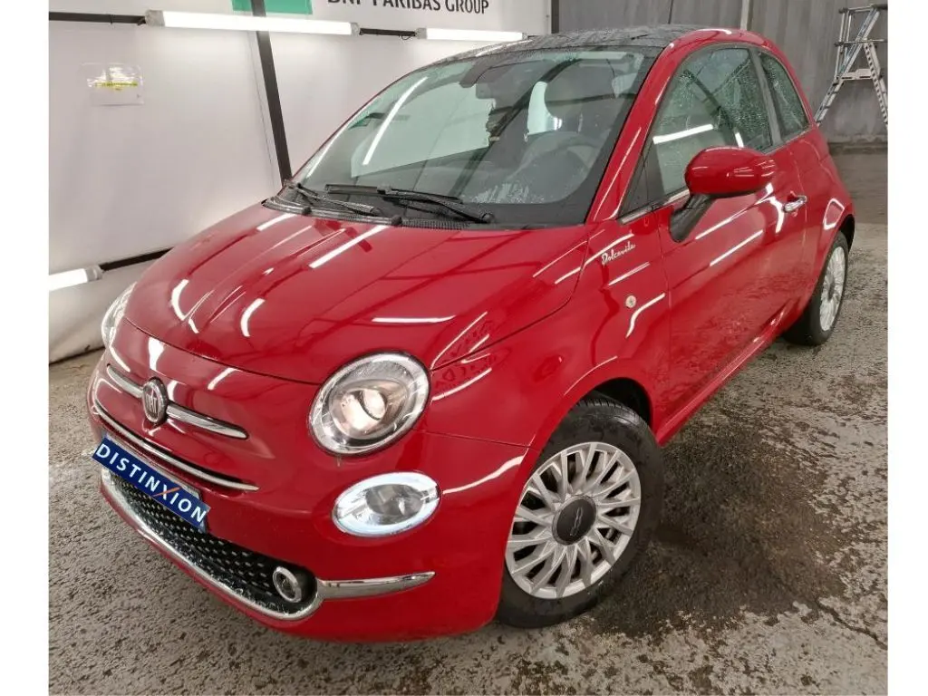 Vue 3/4 avant droite d'une Fiat 500 Dolcevita rouge brillante avec jantes spécifiques et badge distinctif sur aile avant.