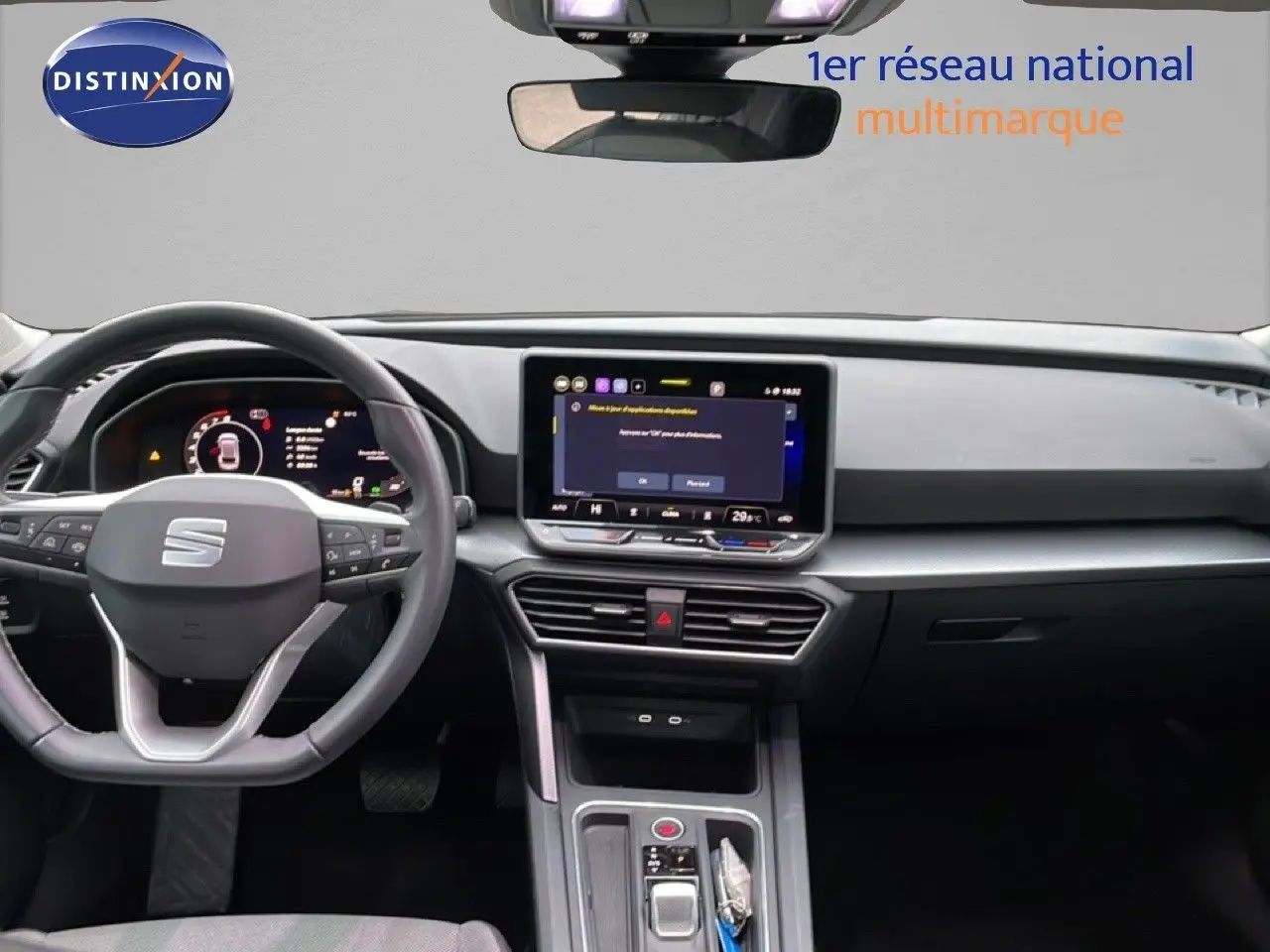 Vue intérieure du tableau de bord et volant du SEAT Leon gris Fiord, avec écran tactile central allumé.
