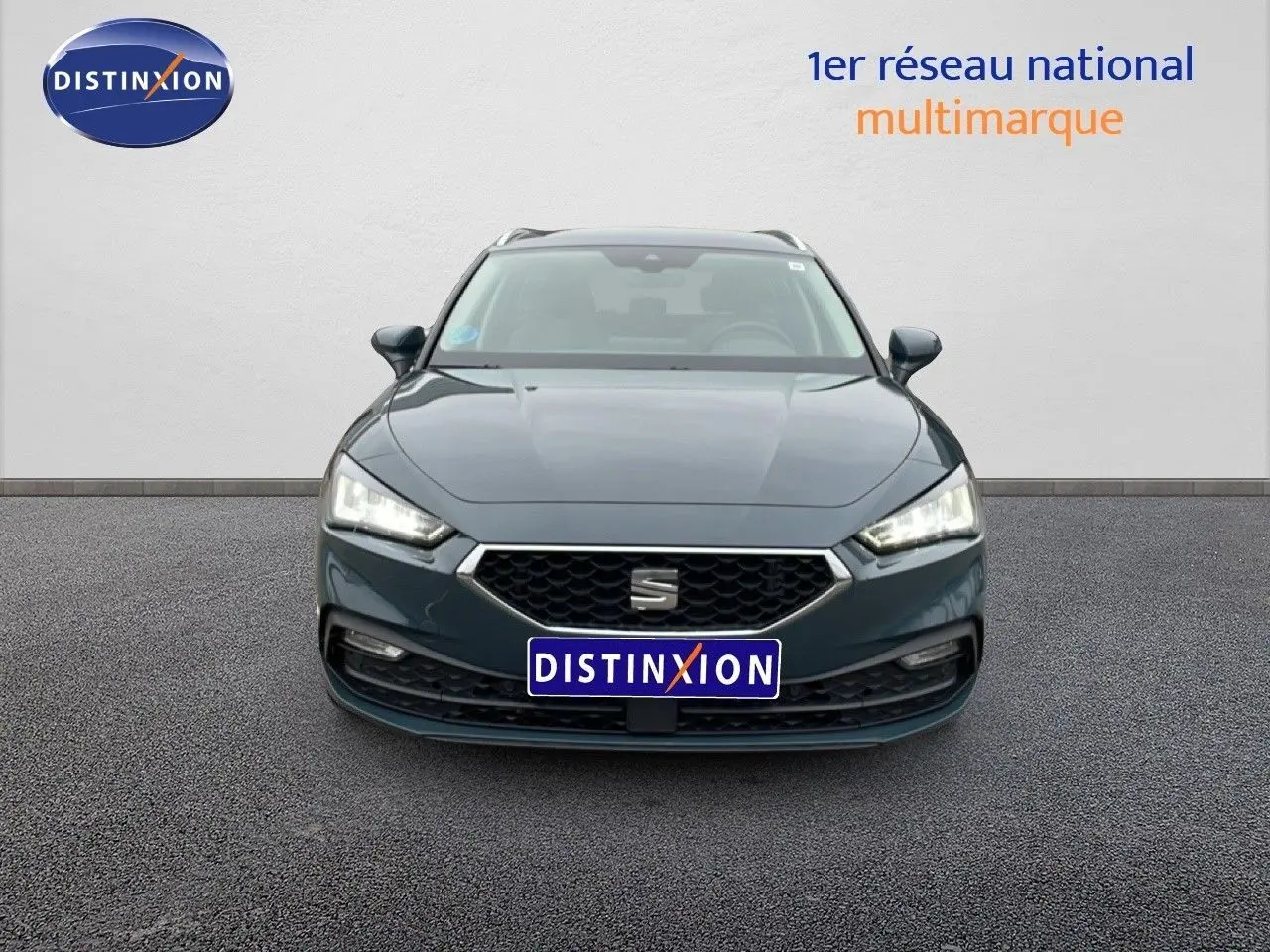 Vue frontale d'une SEAT Leon IV gris fiord, mettant en valeur sa calandre hexagonale et ses phares LED allumés.