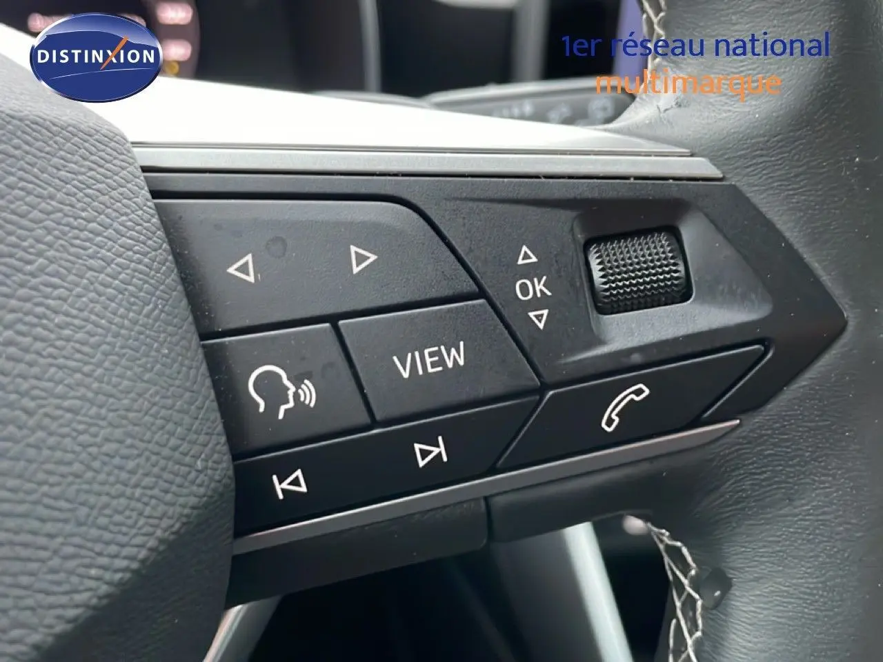 Gros plan sur les commandes au volant noir du SEAT Leon IV gris Fiord, version 25e anniversaire, avec boutons multifonctions visibles.