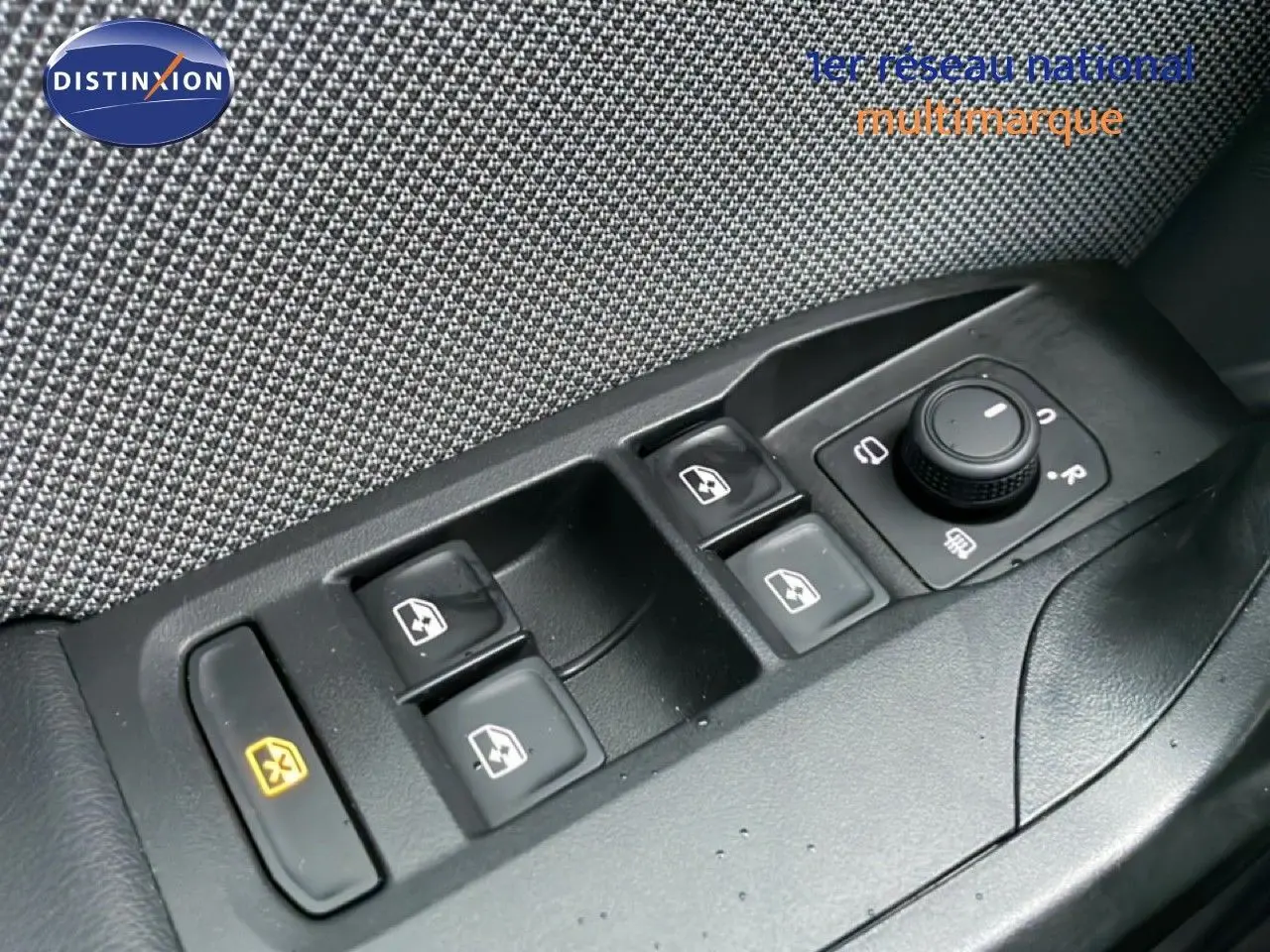 Gros plan sur les commandes des vitres électriques et rétroviseurs d’une SEAT Leon gris Fiord, côté conducteur.