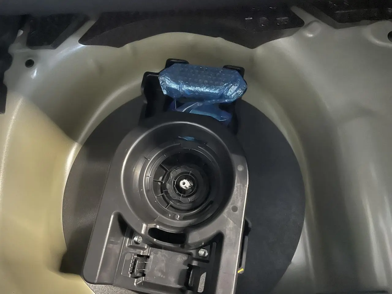 Détail du coffre montrant le logement de la roue de secours de la Peugeot 208 gris clair 2024.