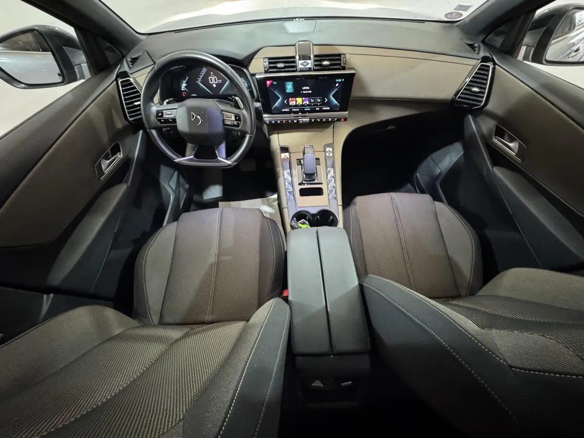Vue intérieure avant du DS7 Crossback E-TENSE gris foncé, avec volant cuir multifonctions et écran tactile central lumineux.