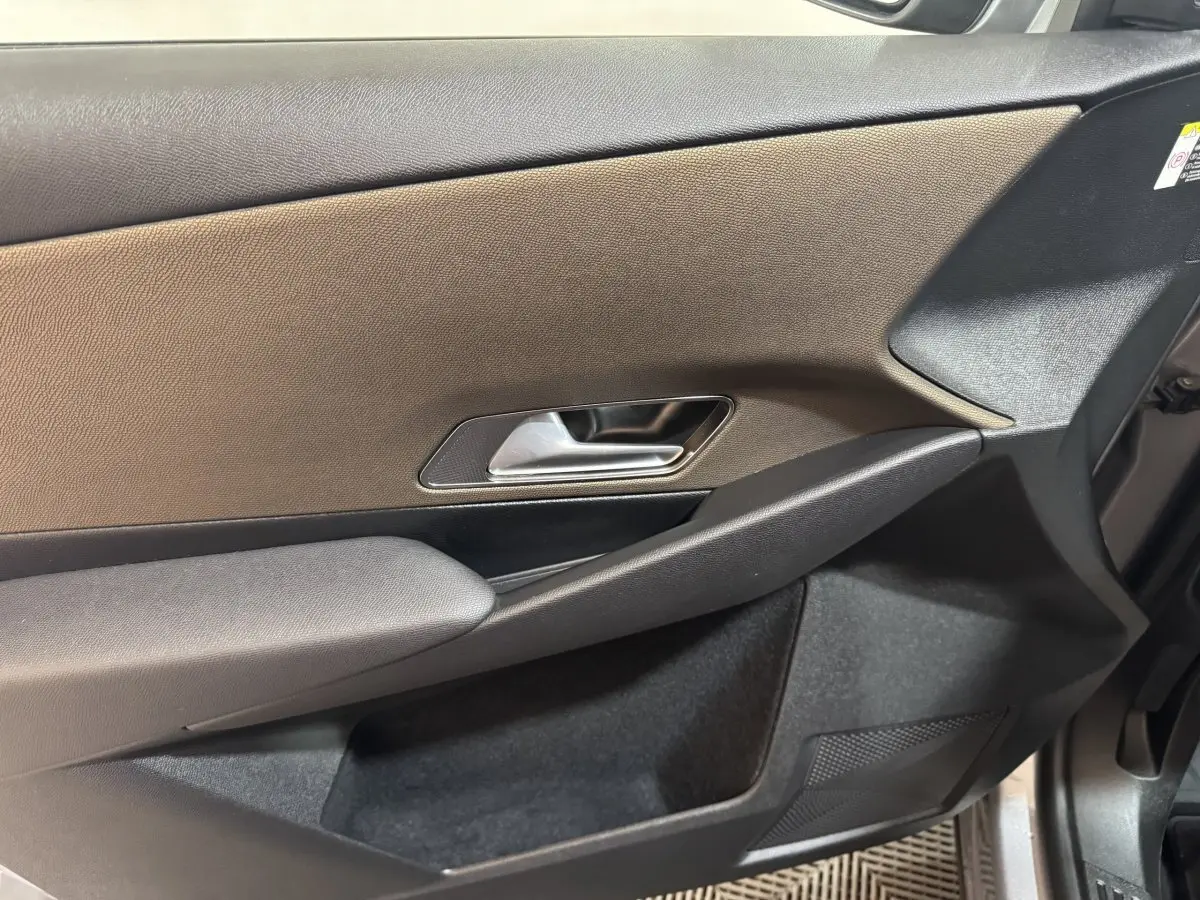 Vue rapprochée de la porte intérieure côté droit du DS7 Crossback gris foncé, avec poignée argentée et accoudoir textile.