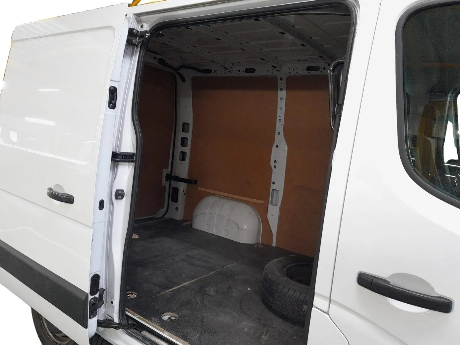 Vue latérale droite du Renault Master blanc 2023 avec porte coulissante ouverte montrant l'espace de chargement vide et une roue de secours.