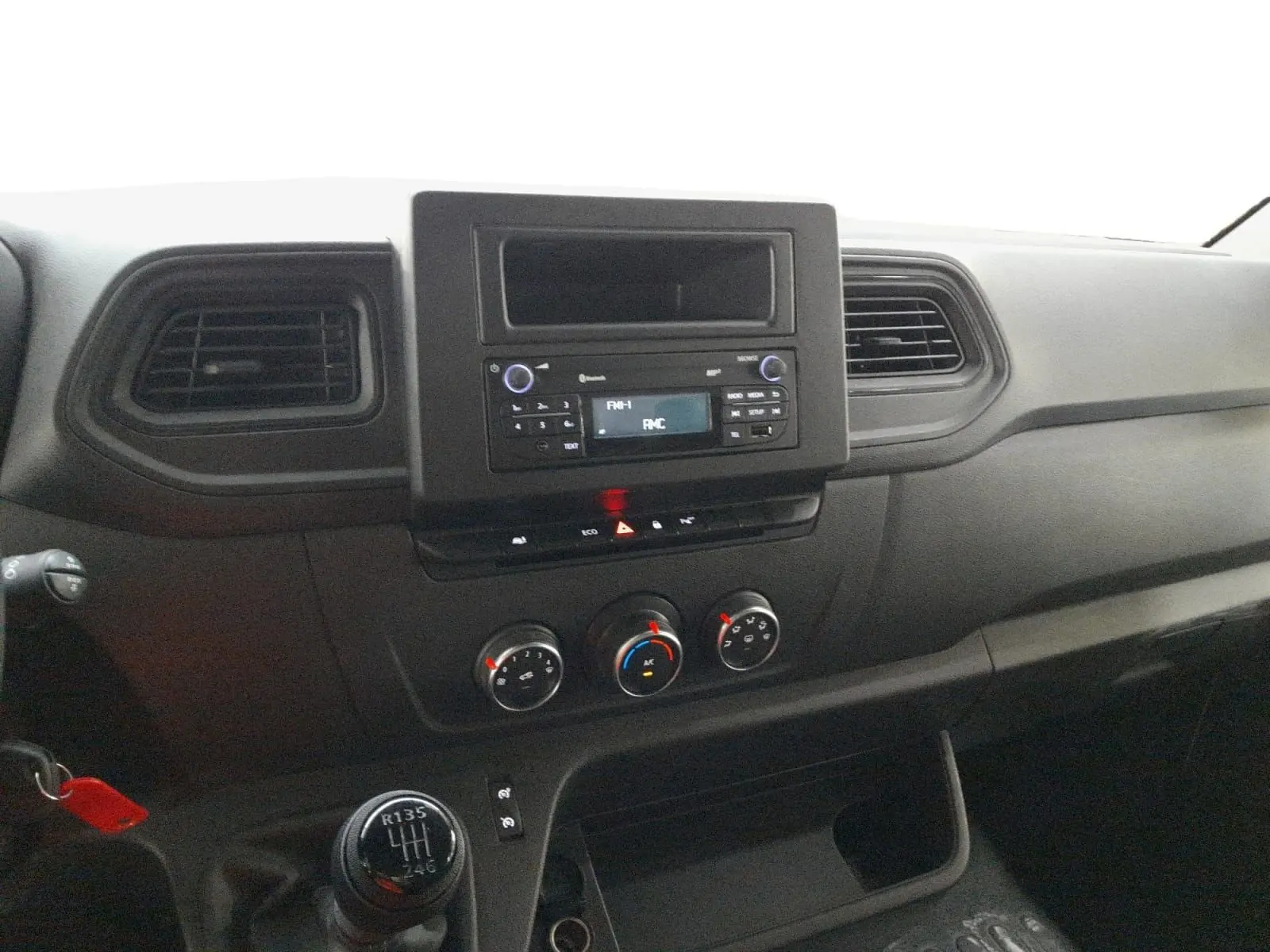 Vue intérieure du tableau de bord du Renault Master blanc 2023, avec console centrale, commandes clim et levier de vitesses manuel.