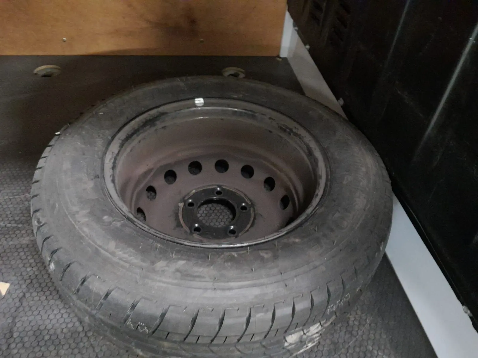 Pneu de secours noir posé dans l’espace de chargement du Renault Master blanc, vue en plongée rapprochée.