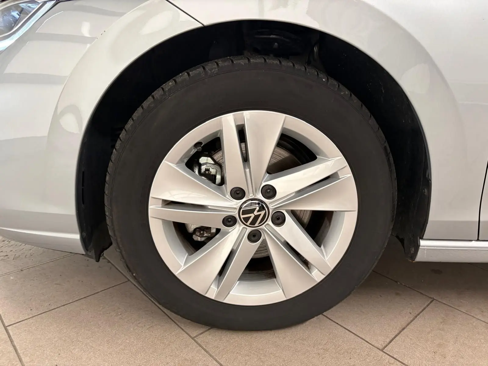 Gros plan sur la roue avant droite d'une Volkswagen Golf 2025 reflet d'argent avec jante alliage à cinq branches doubles.