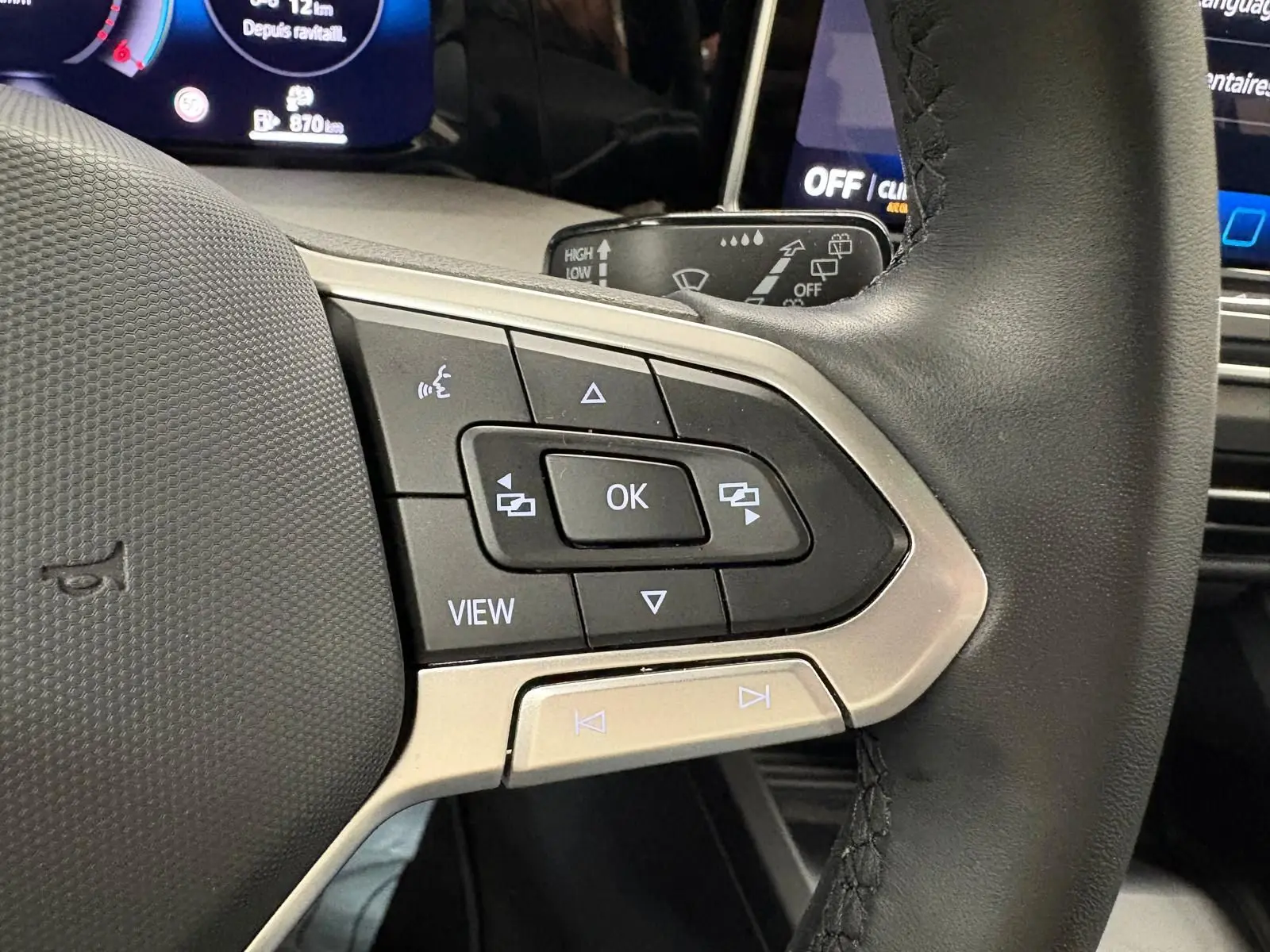 Gros plan sur les commandes multifonctions à gauche du volant noir de la Volkswagen Golf 2.0 TDI 2025 finition Life Plus.