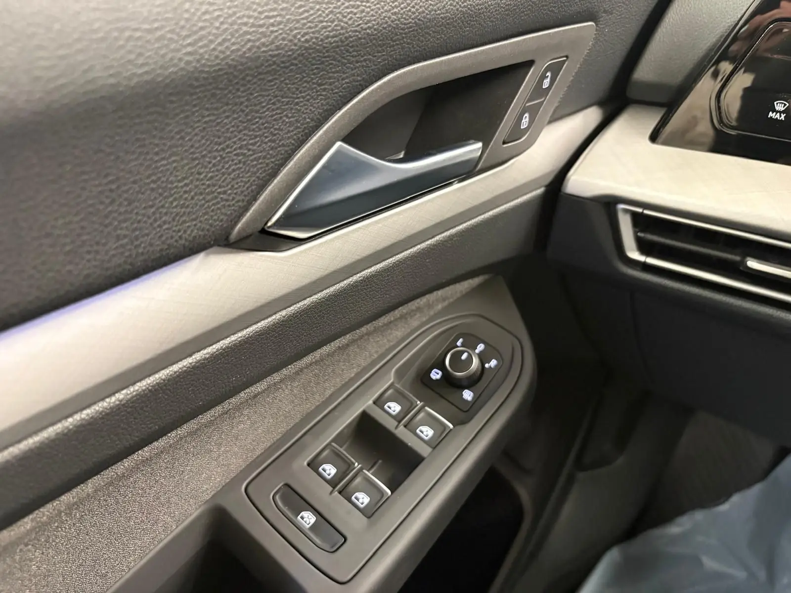 Détail intérieur côté conducteur de la Volkswagen Golf 2025, montrant les commandes des vitres et la poignée de porte en reflet d'argent.