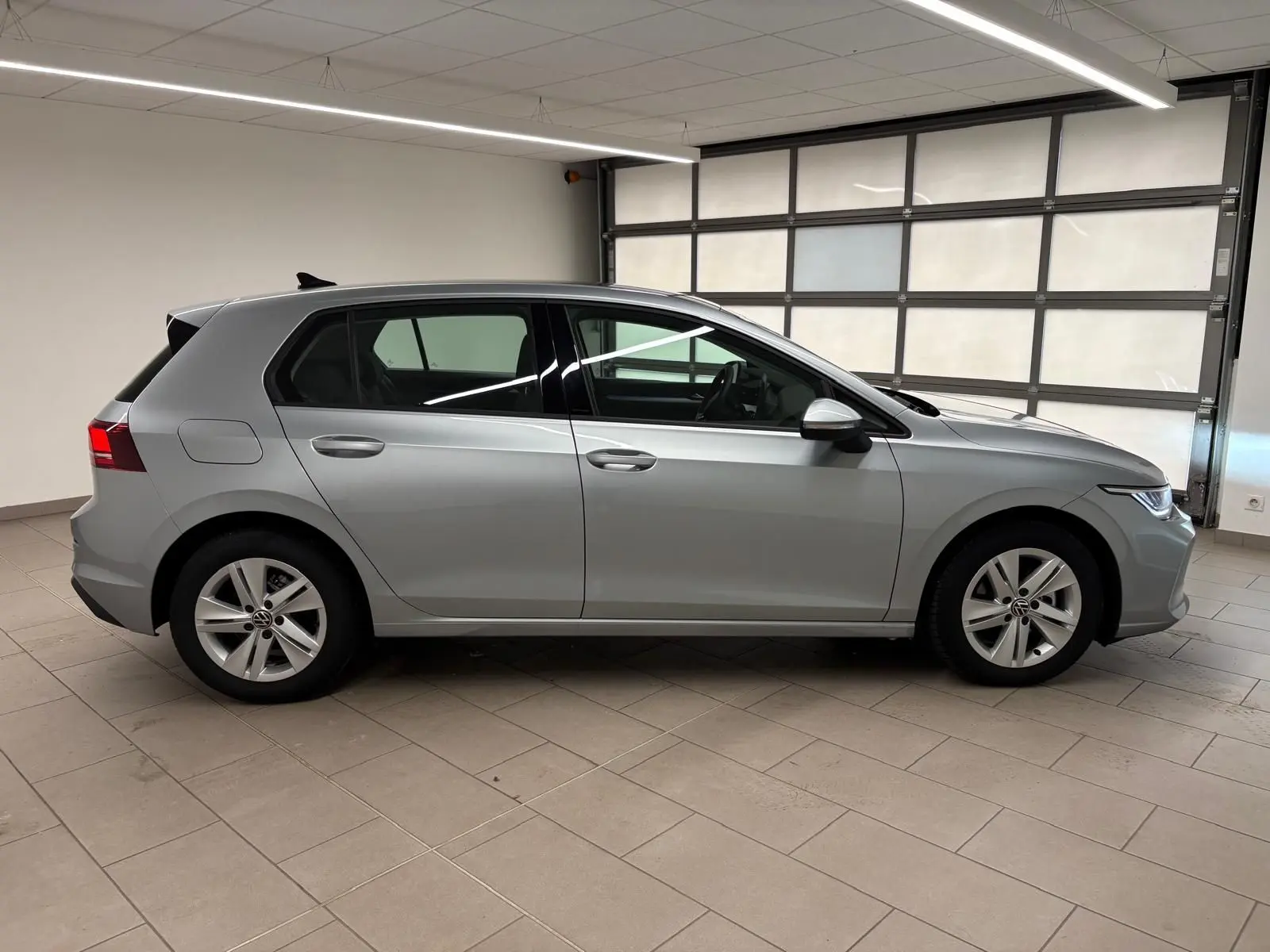Vue latérale droite d'une Volkswagen Golf 2.0 TDI 116 BVM6 Life Plus 2025 en reflet d'argent dans un garage.