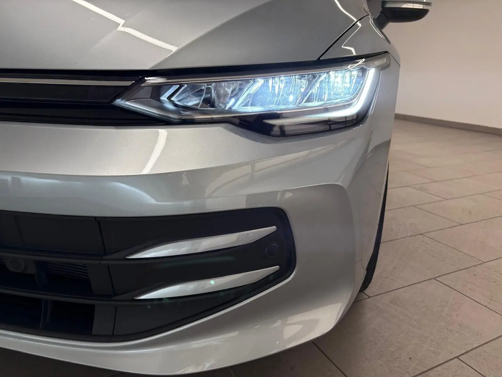 Gros plan sur l'avant droit d'une Volkswagen Golf 2.0 TDI 116 BVM6 Life Plus 2025 en reflet argent avec phares allumés.