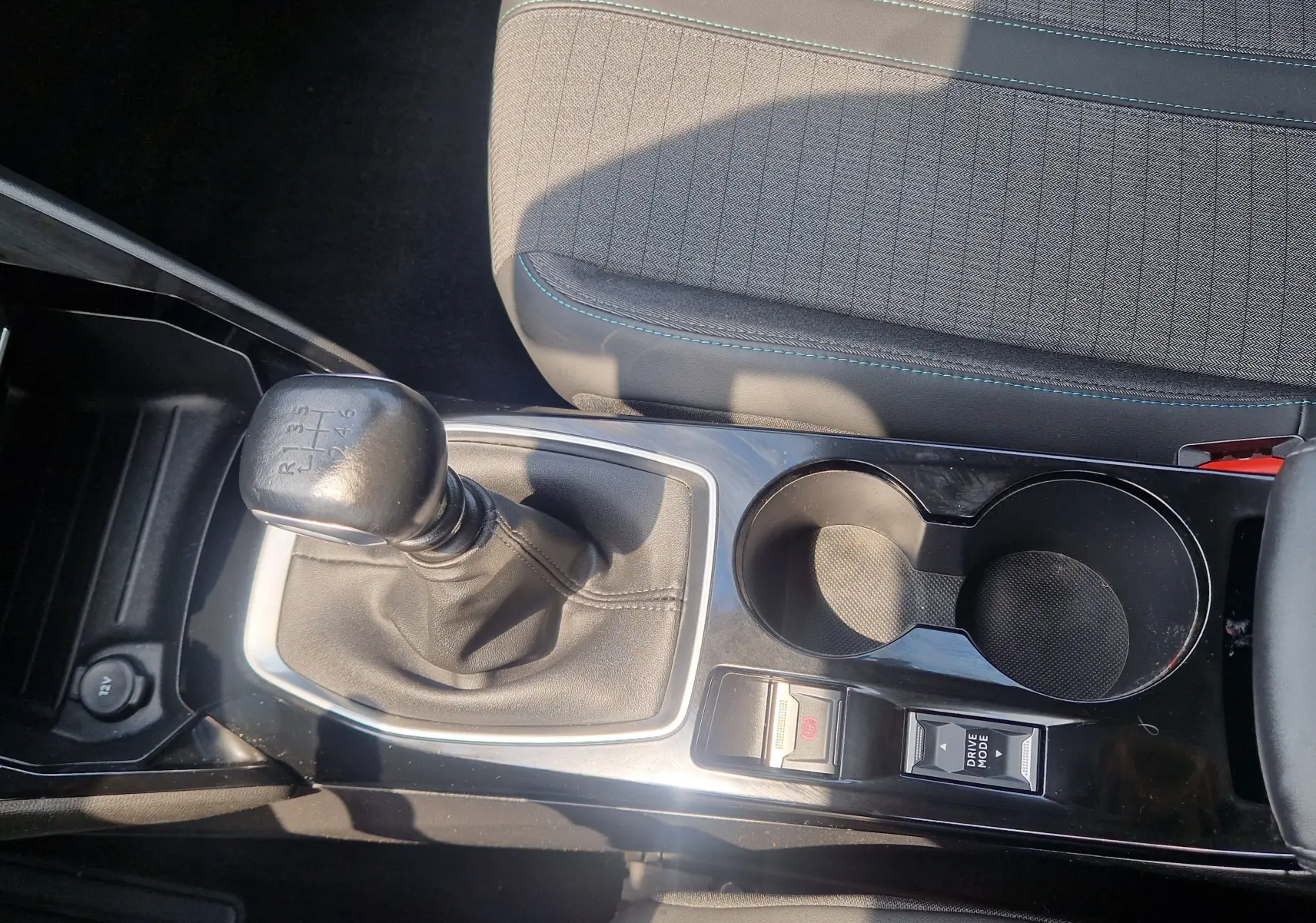 Vue rapprochée de la console centrale d'une Peugeot 208 bleu Vertigo 2022 avec levier de vitesse manuel et porte-gobelets.