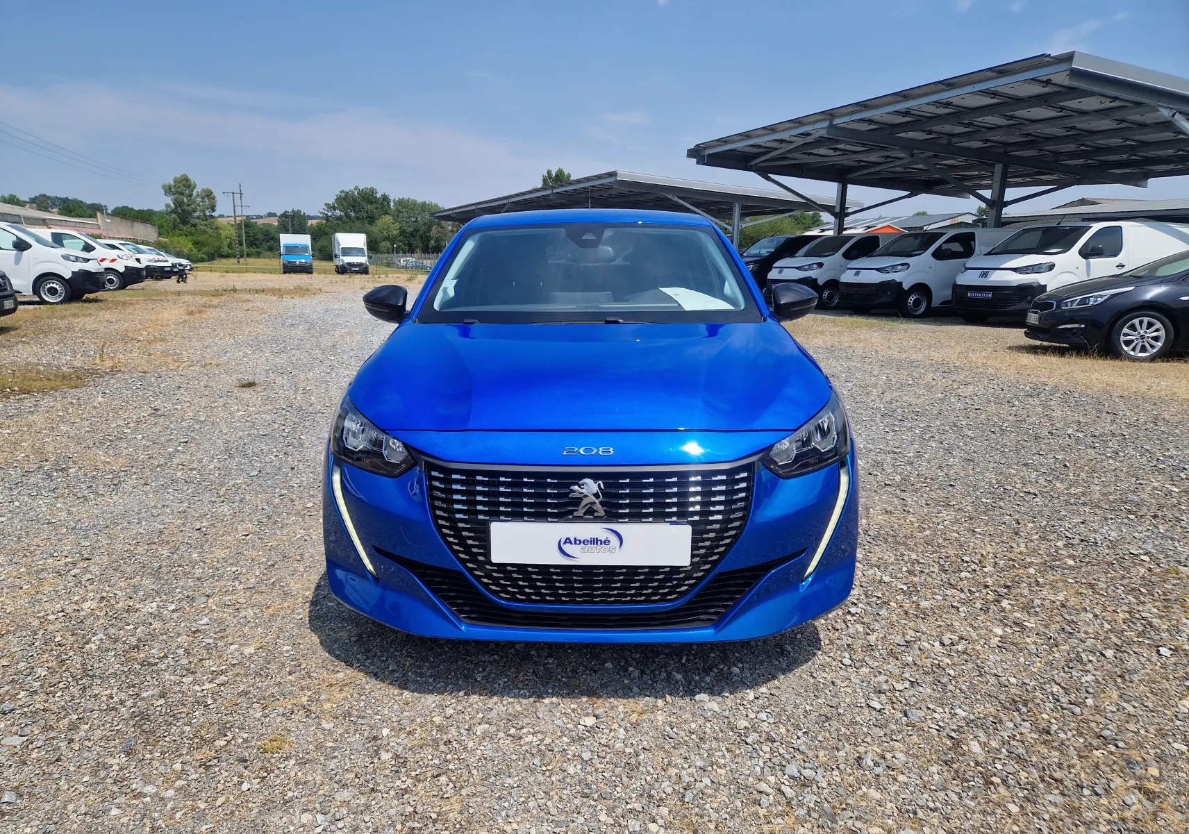 Vue de face d'une Peugeot 208 1.2 PureTech 110 Allure Pack bleu Vertigo, avec calandre distinctive et feux LED en forme de griffes.