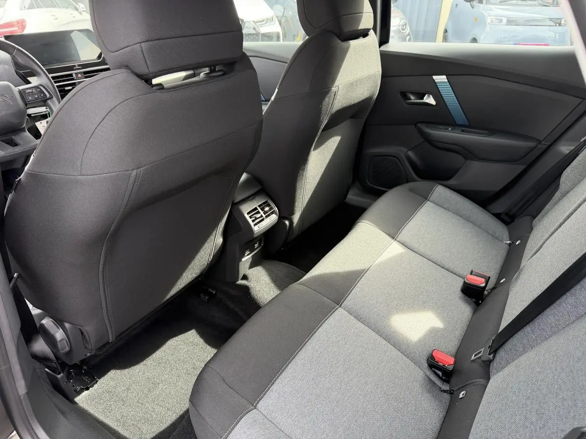 Vue intérieure arrière côté droit de la banquette tissu gris et noir du Citroën C4 ë-136 2025 avec aérateurs centraux.