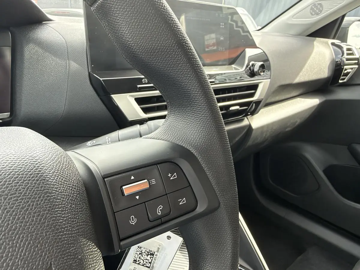Vue rapprochée du volant et tableau de bord noir de la Citroën C4 ë-136 2025 avec commandes intégrées au volant.