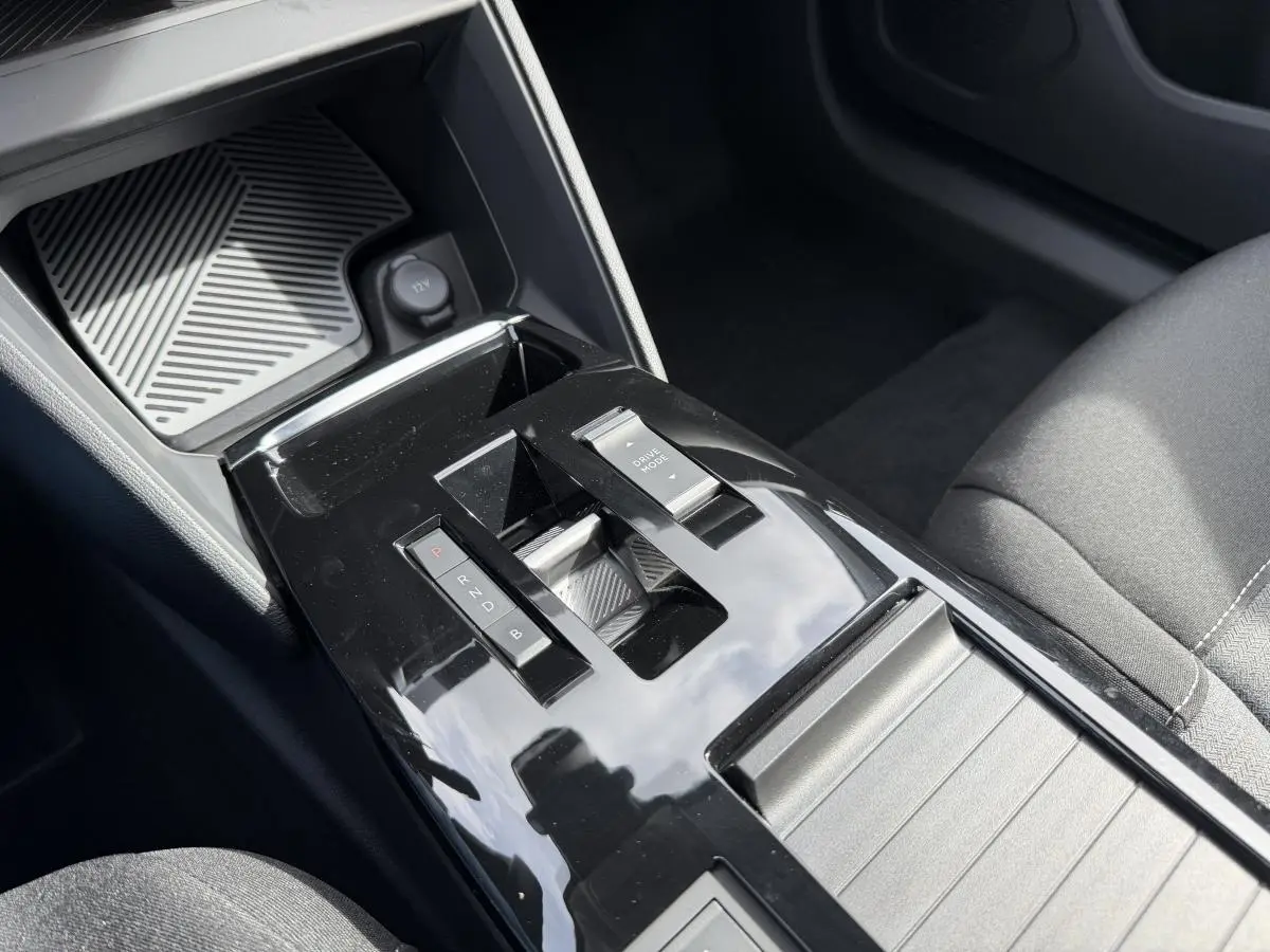 Gros plan sur la console centrale noire brillante de la Citroën ë-C4 2025 avec levier de vitesses automatique et bouton Drive Mode.